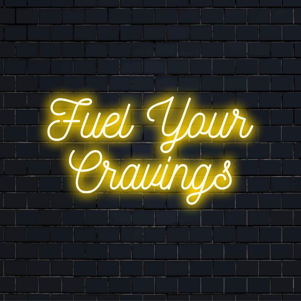 Op maat gemaakt LED-neonbord met de tekst Fuel Your Cravings, met modern typografisch ontwerp en levendige neonkleuren.