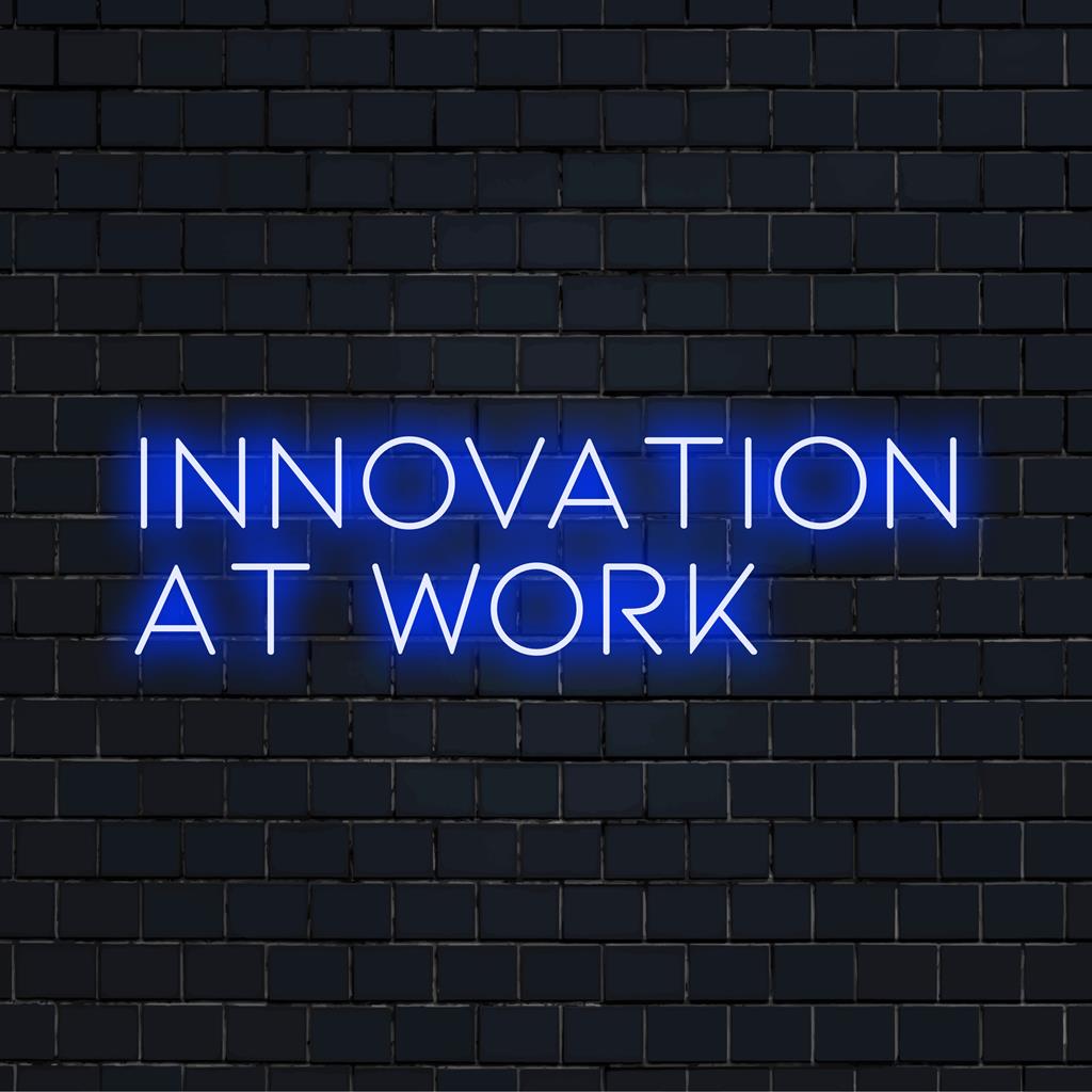 Op maat gemaakt LED-neonbord met de tekst Innovation At Work, gloeiend in levendige kleuren, perfect voor een moderne kantoorinrichting.