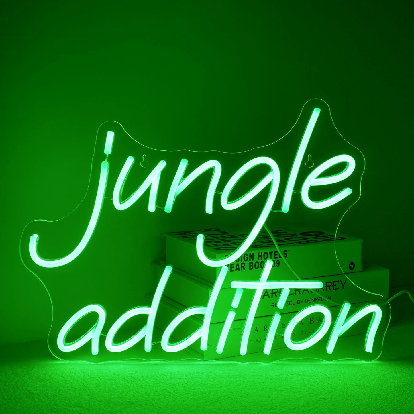 Een levendig groen "Jungle Addition" LED-neonbord, tegen een minimalistische witte muurachtergrond.