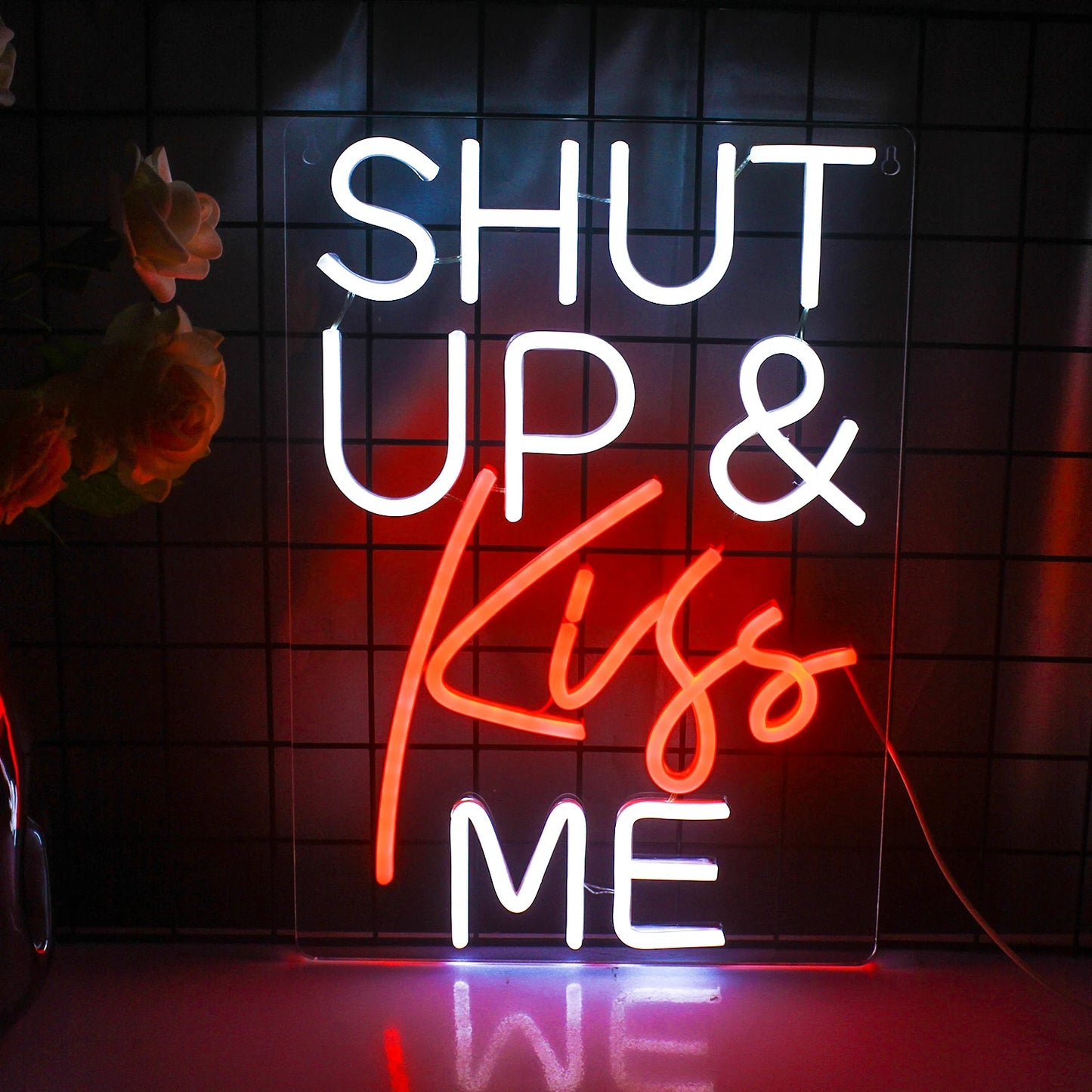 Op de afbeelding is een opvallend led-neonbord te zien met de tekst "Shut Up Kiss Me" in een speels, cursief schrift.