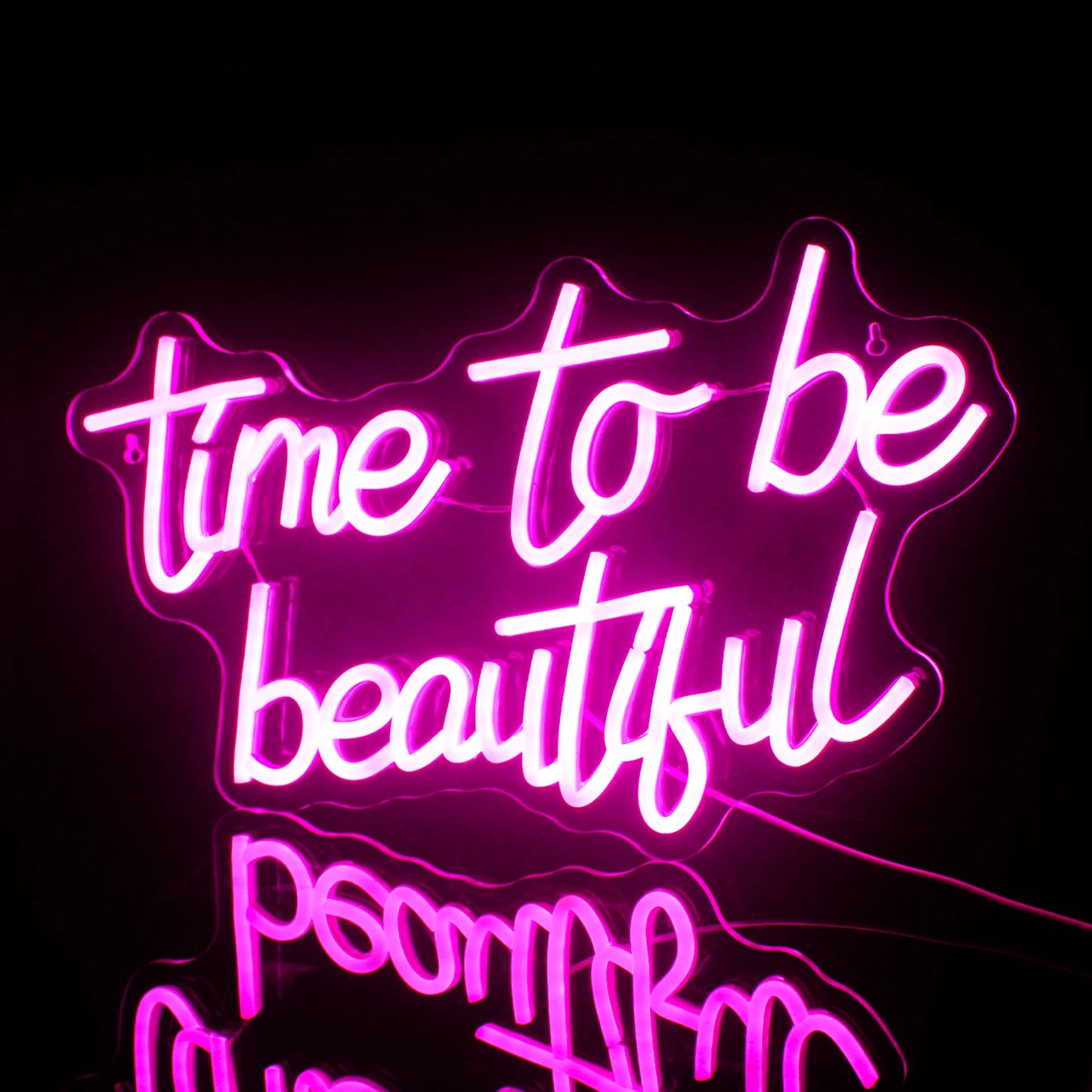 Een levendig "Time to be Beautiful" LED-neonbord tegen een minimalistische donkergrijze muur.