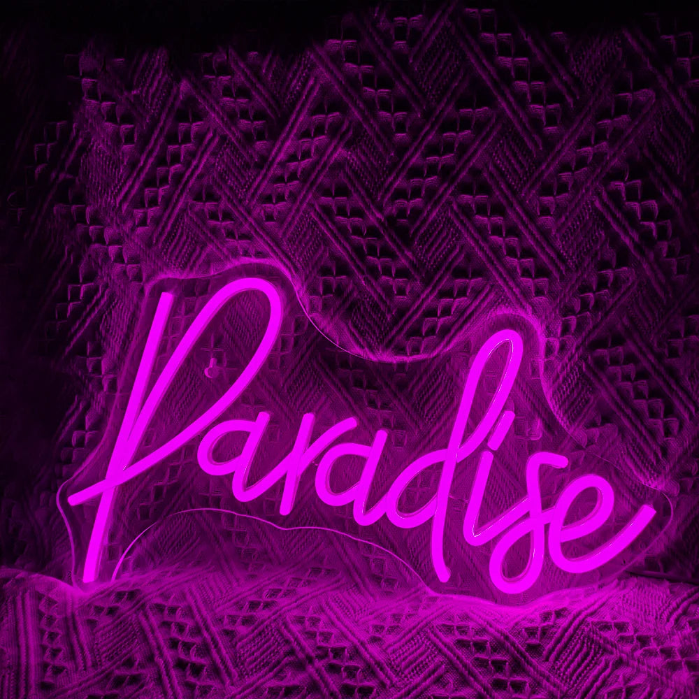 Op de afbeelding is een levendig, handgemaakt LED-neonbord te zien waarop het woord 'Paradise' in een speels, cursief lettertype staat.