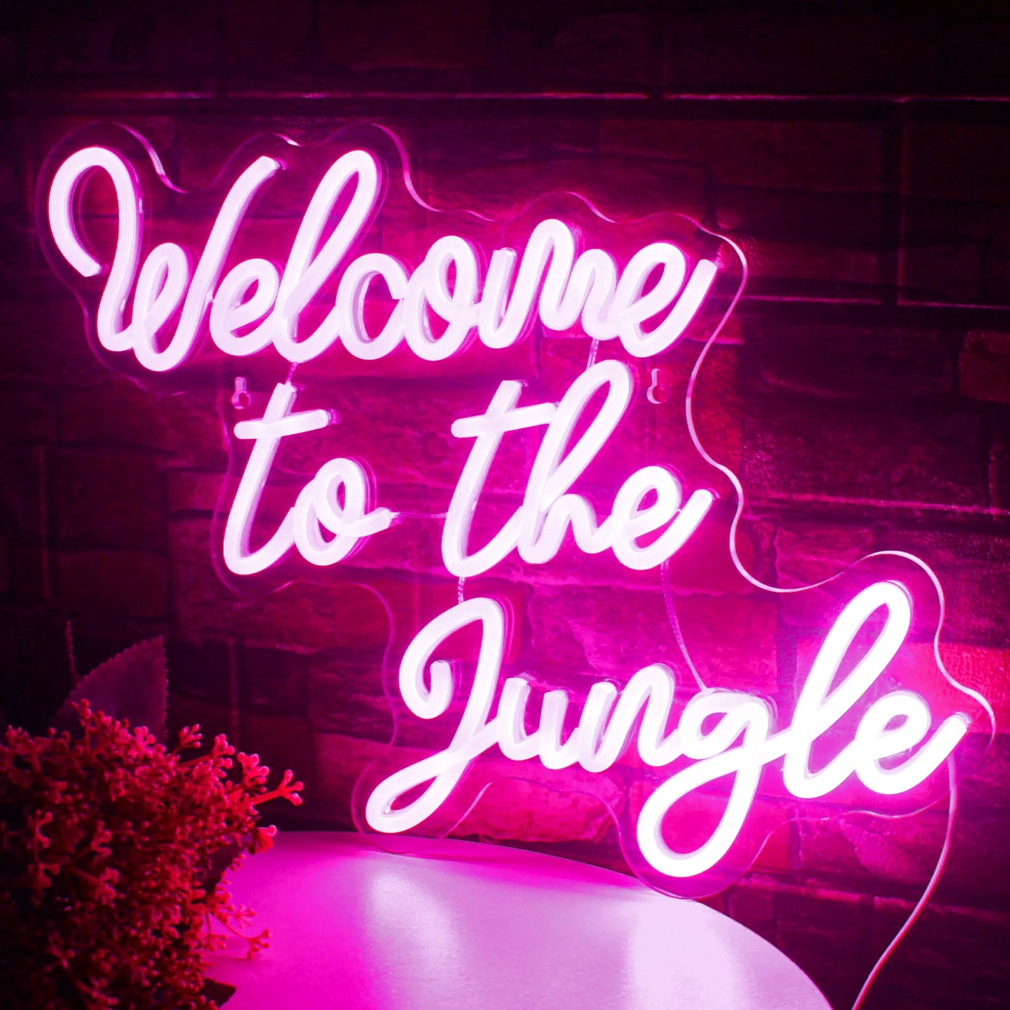 De afbeelding toont een levendig LED-neonbord met de tekst "Welcome to the Jungle" in opvallende, cursieve letters.