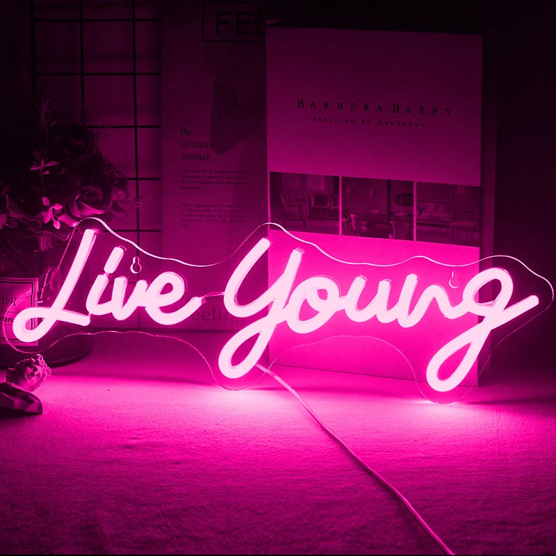 Op de afbeelding is een levendig handgemaakt LED-neonbord te zien met de tekst "Live Young" in een levendig, cursief schrift.