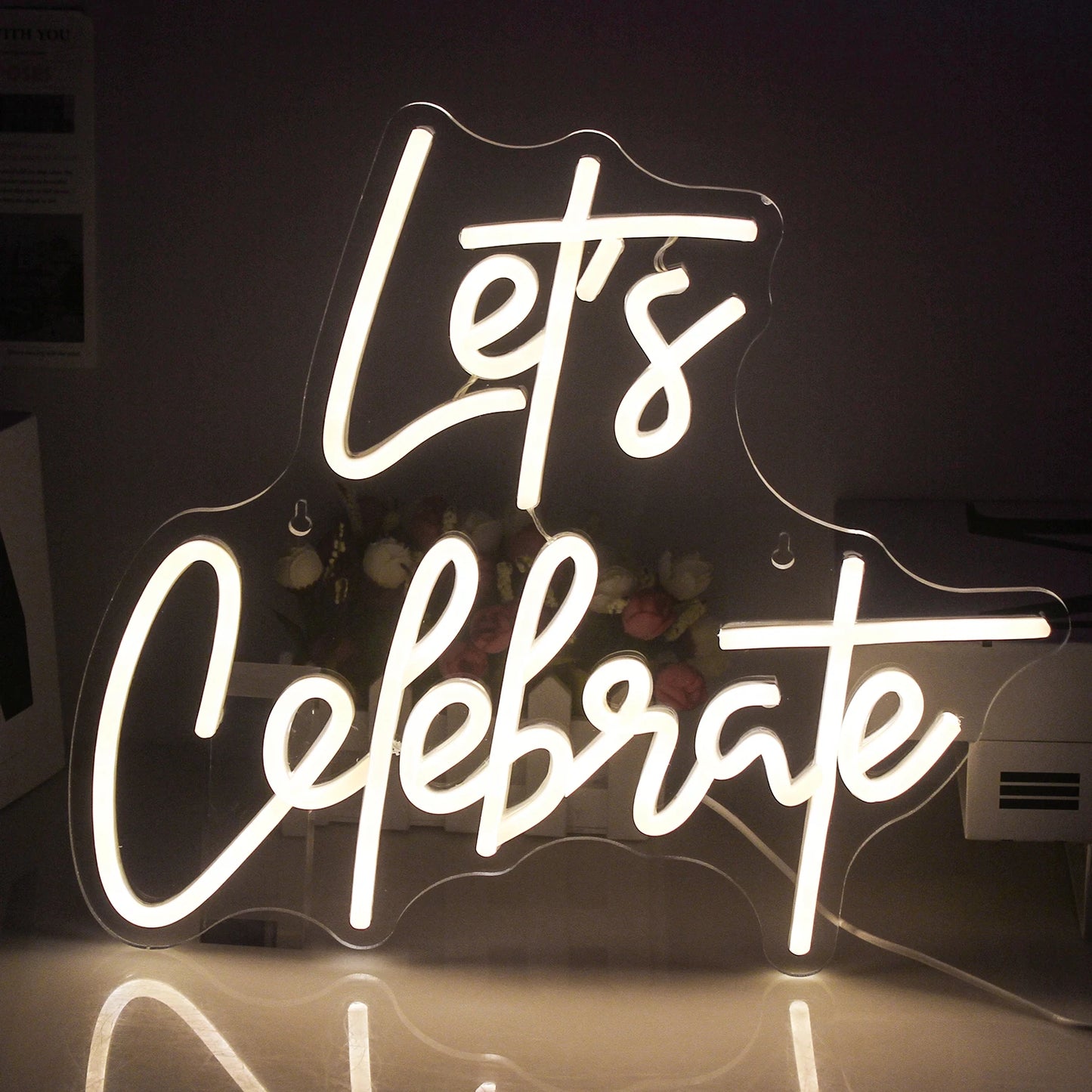 Op de afbeelding staat een levendig LED-neonbord met de tekst "Let's Celebrate".