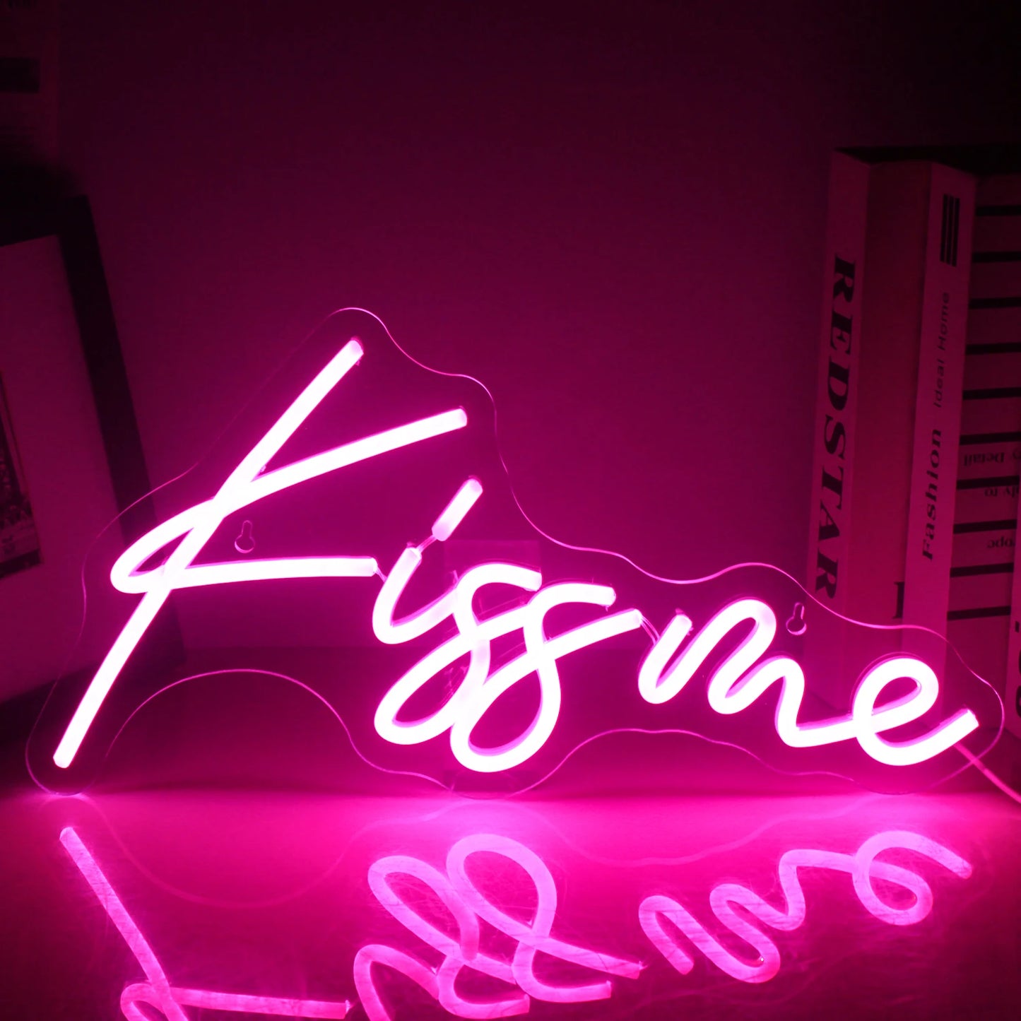 Een levendig "Kiss Me" LED-neonbord is verlicht, met felle, opvallende roze letters op een donkere achtergrond.