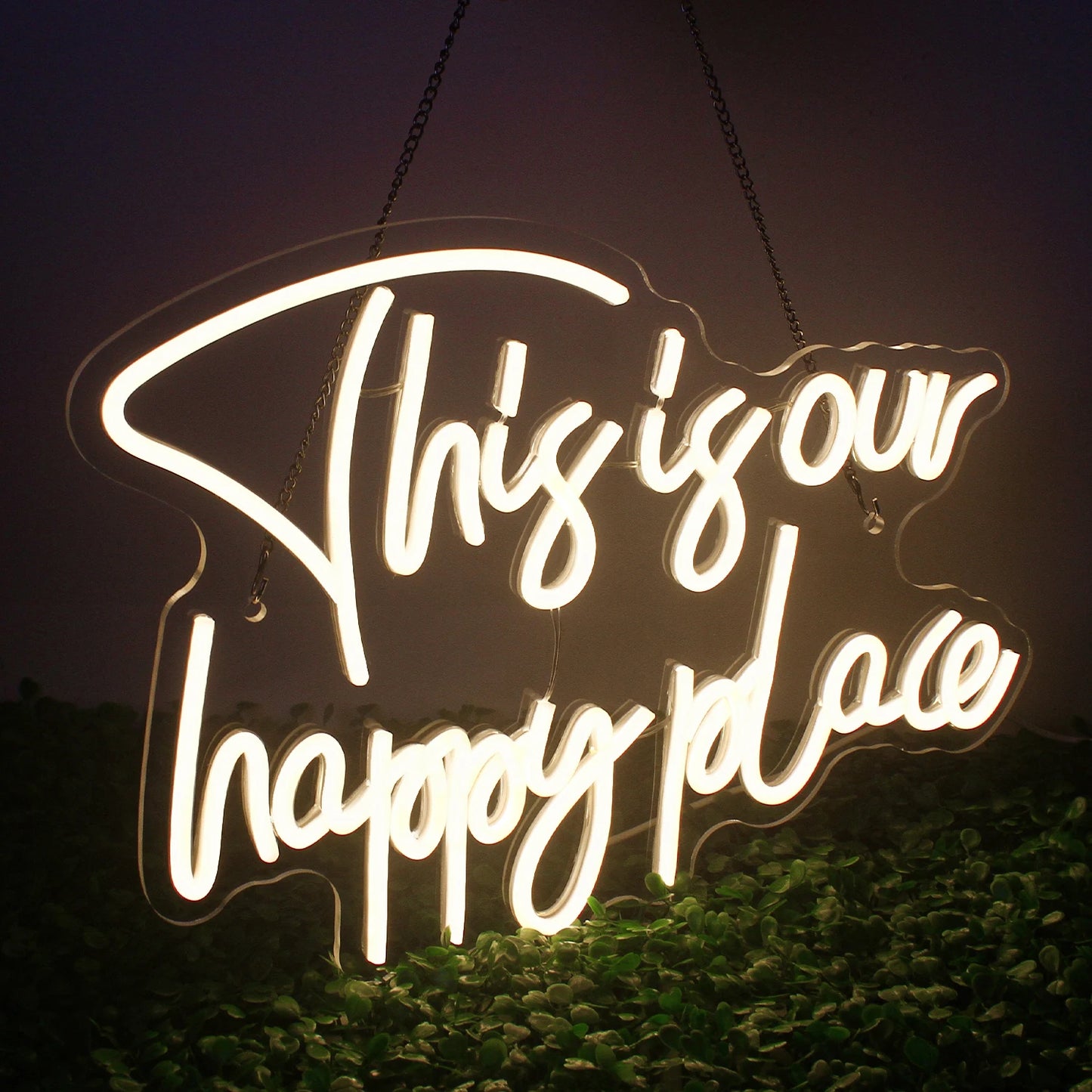 Op de afbeelding staat een opvallend led-neonbord met de tekst "This is our happy place" in schuinschrift.