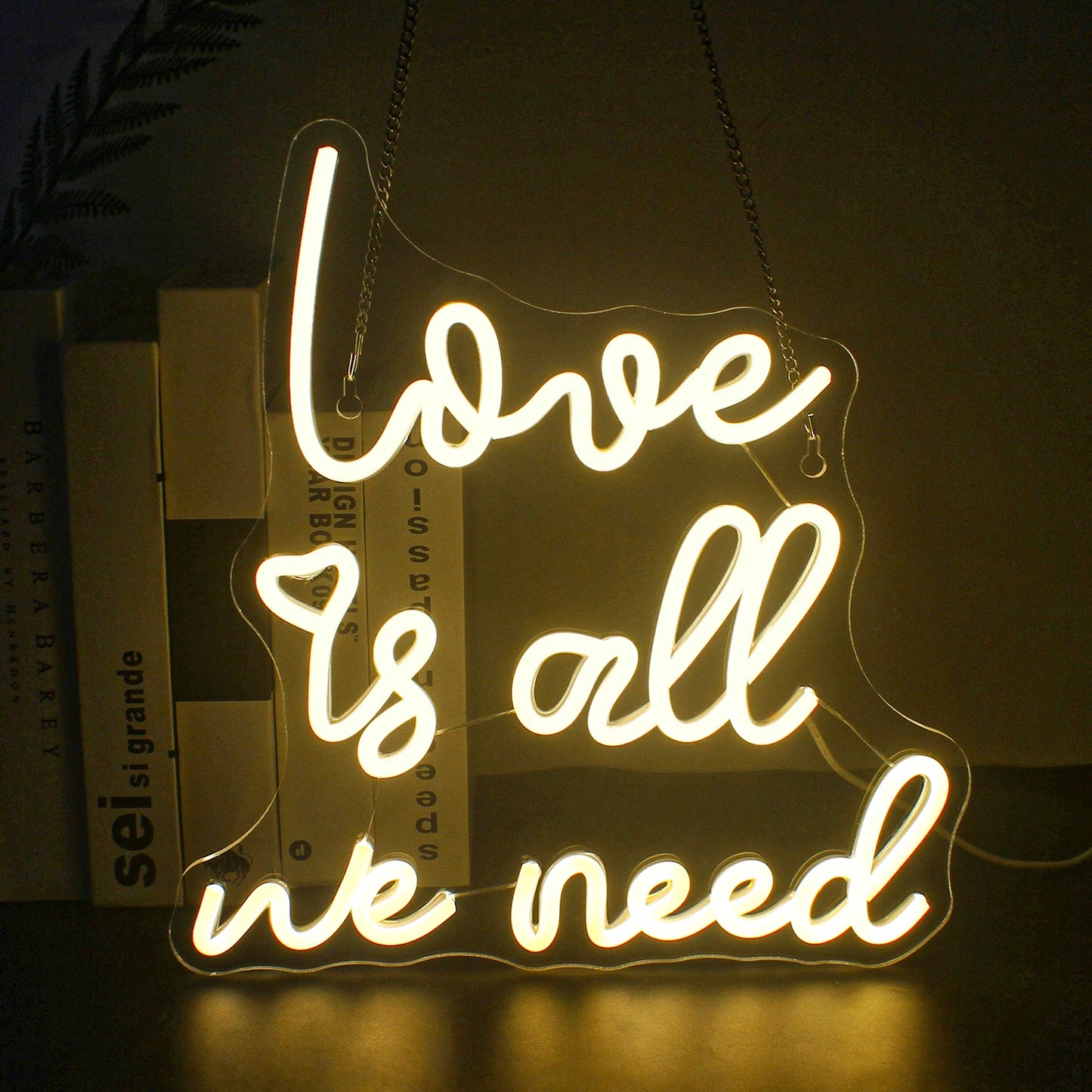 Op de afbeelding staat een opvallend led-neonbord met de tekst "Love is all we need" in een vloeiend, cursief lettertype.