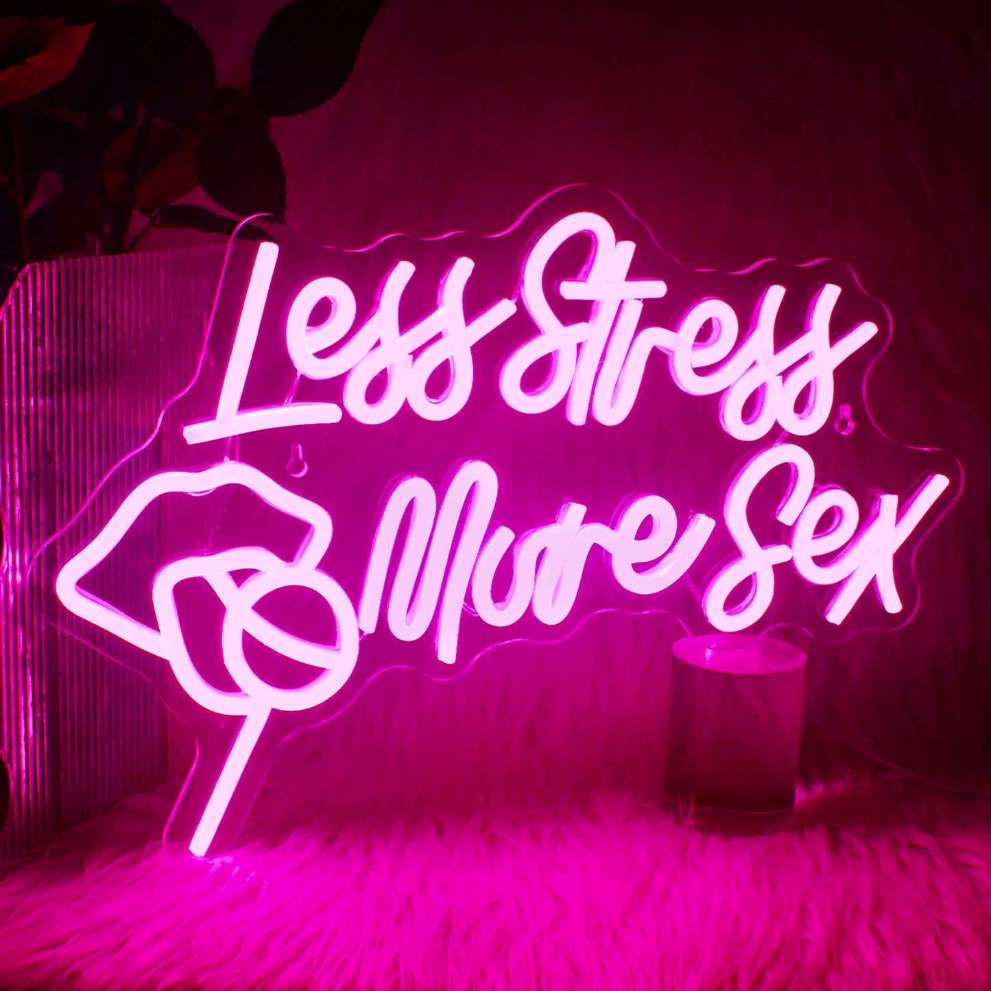 Een levendig LED-neonbord met de tekst "Less Stress More Sex" in een stijlvol, cursief lettertype.