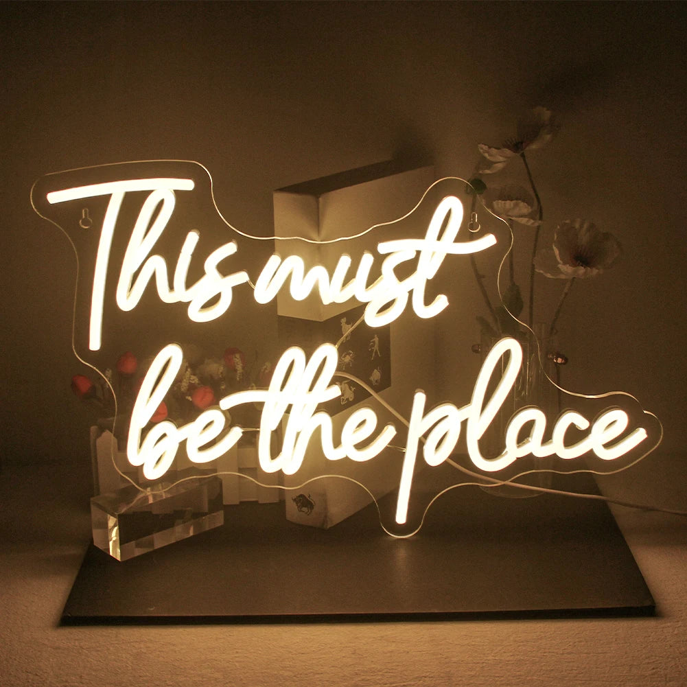 Op de afbeelding is een opvallend led-neonbord te zien, waarop in schrift de tekst "This must be the place" staat.