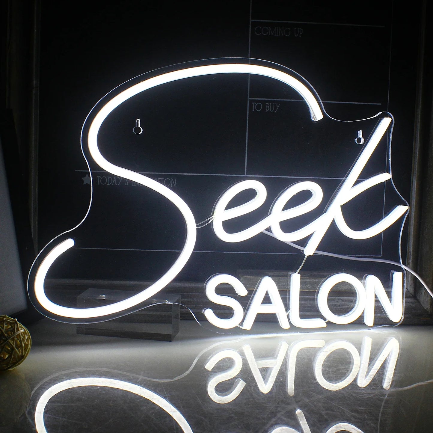 Op de afbeelding staat een opvallend LED-neonbord met het woord "SALON" in gestileerde hoofdletters.