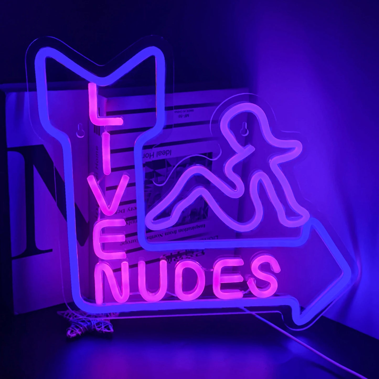 Op de afbeelding staat een levendig LED-neonbord met de tekst "Live Nudes Girl" in speels, cursief schrift.