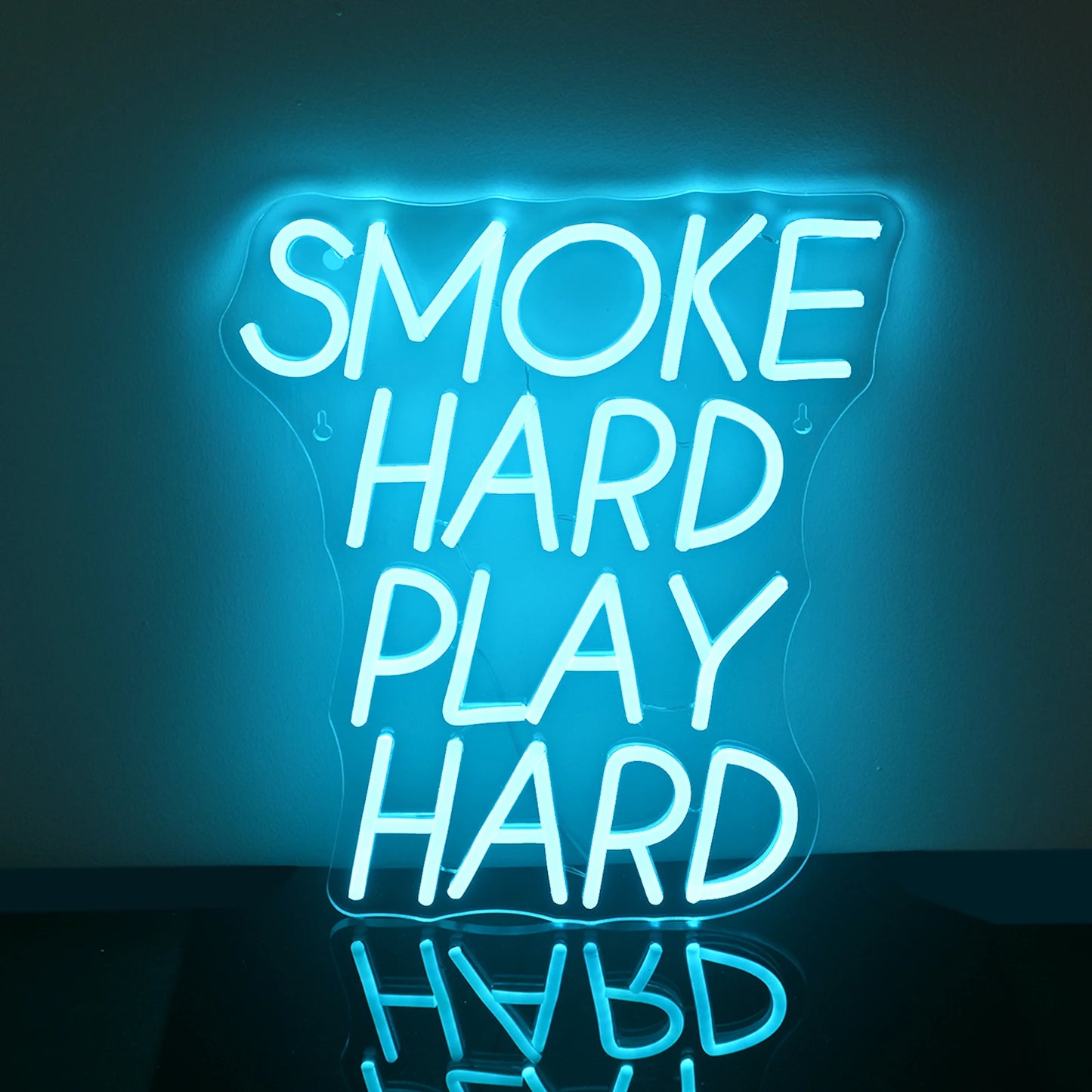 Op de afbeelding is een opvallend LED-neonbord te zien met de tekst "Smoke Hard Play Hard" in vette hoofdletters.