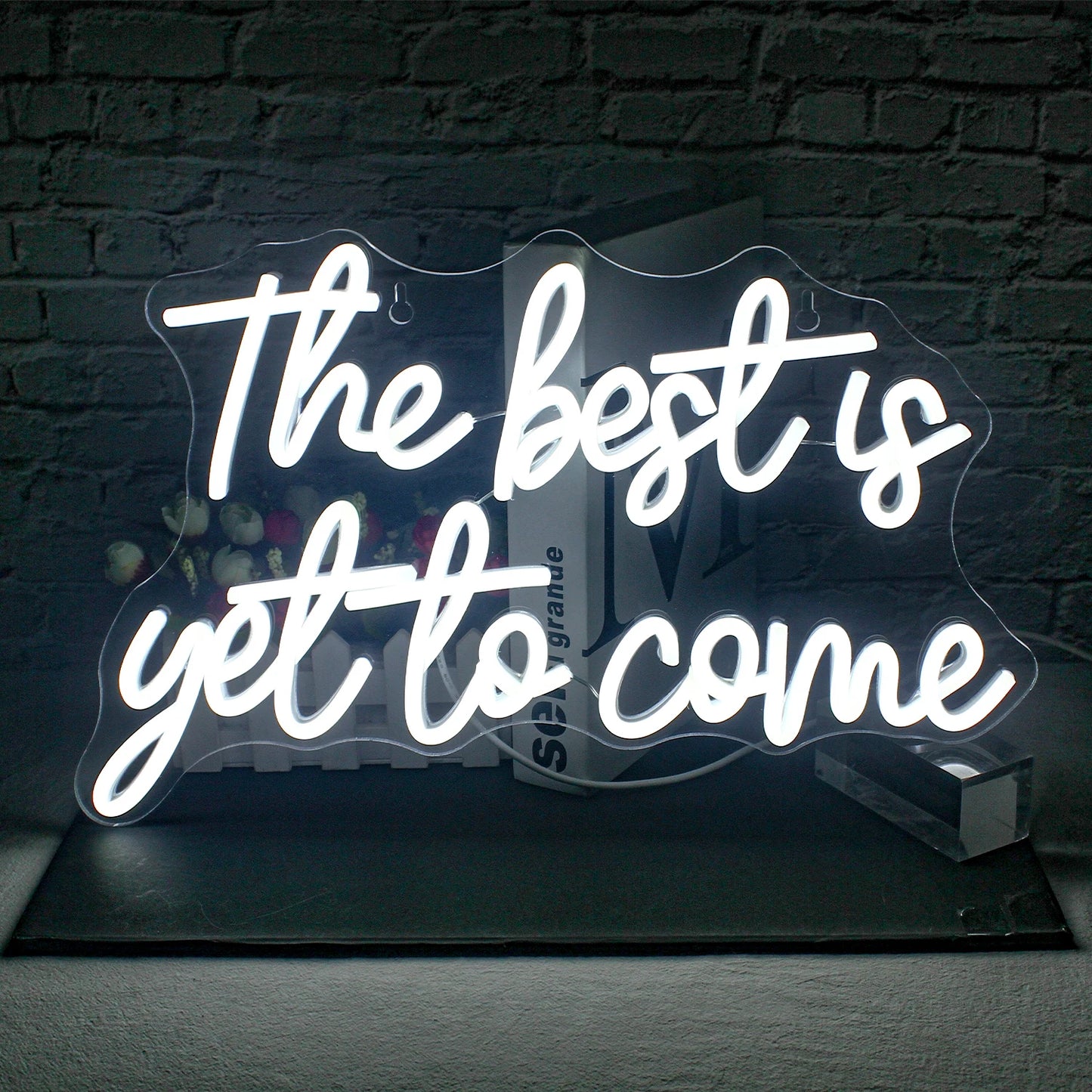 De afbeelding toont een levendig, handgemaakt LED-neonbord met de tekst "The Best is Yet to Come" in een stijlvol, cursief lettertype.