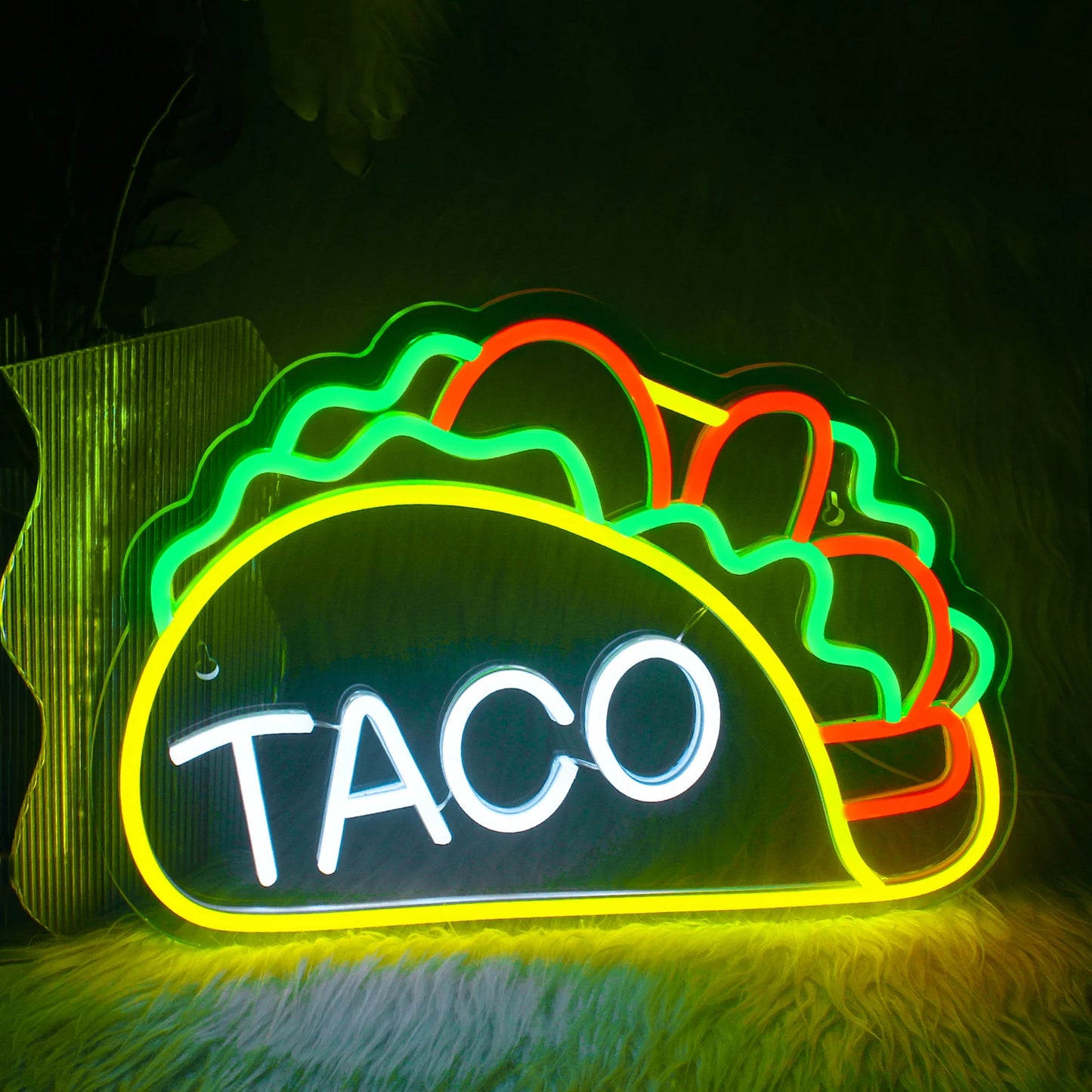Op de afbeelding staat een levendig LED-neonbord in de vorm van het woord 'Tacos'.