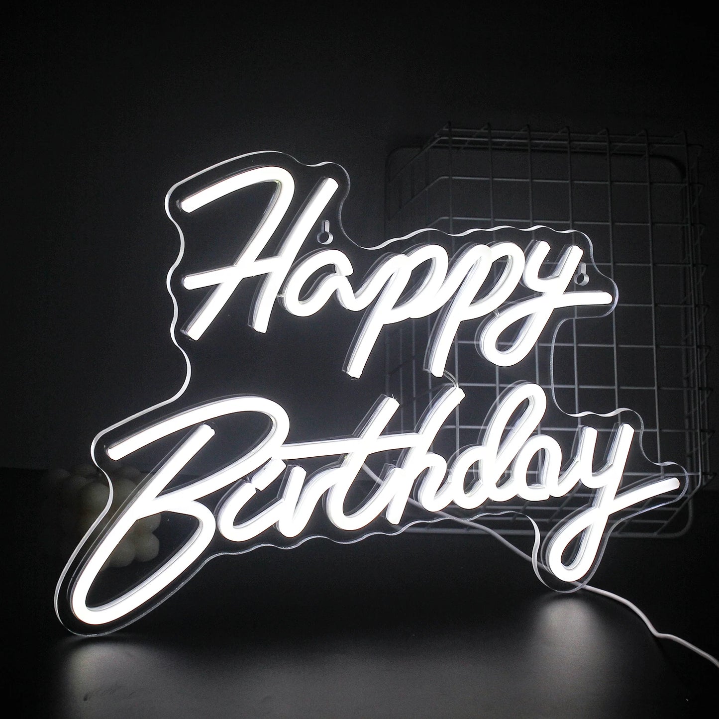 Een levendig "Happy Birthday" LED-neonbord dat warm oplicht tegen een donkere achtergrond.