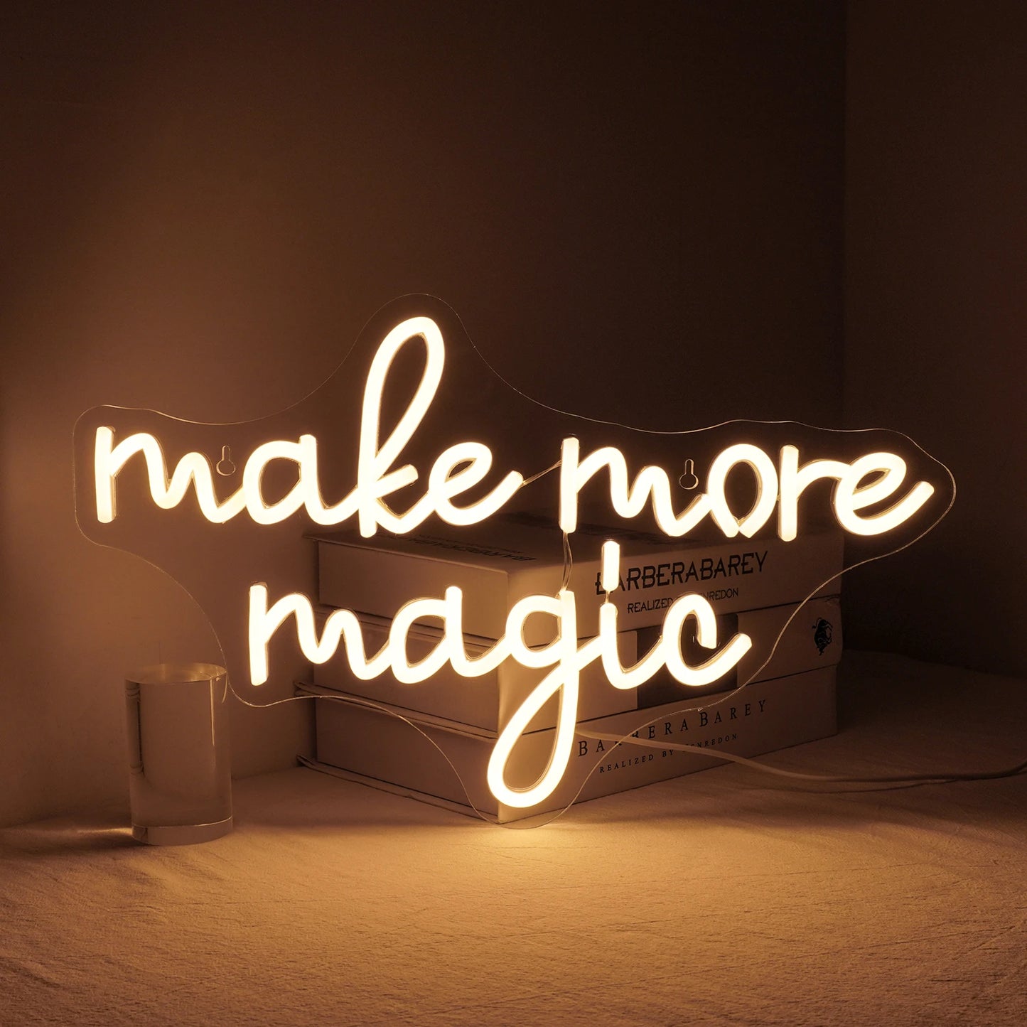 Een levendig "Make More Magic" LED-neonbord in een vrolijke kleurenmix is gemonteerd op een strakke, donkere achtergrond.