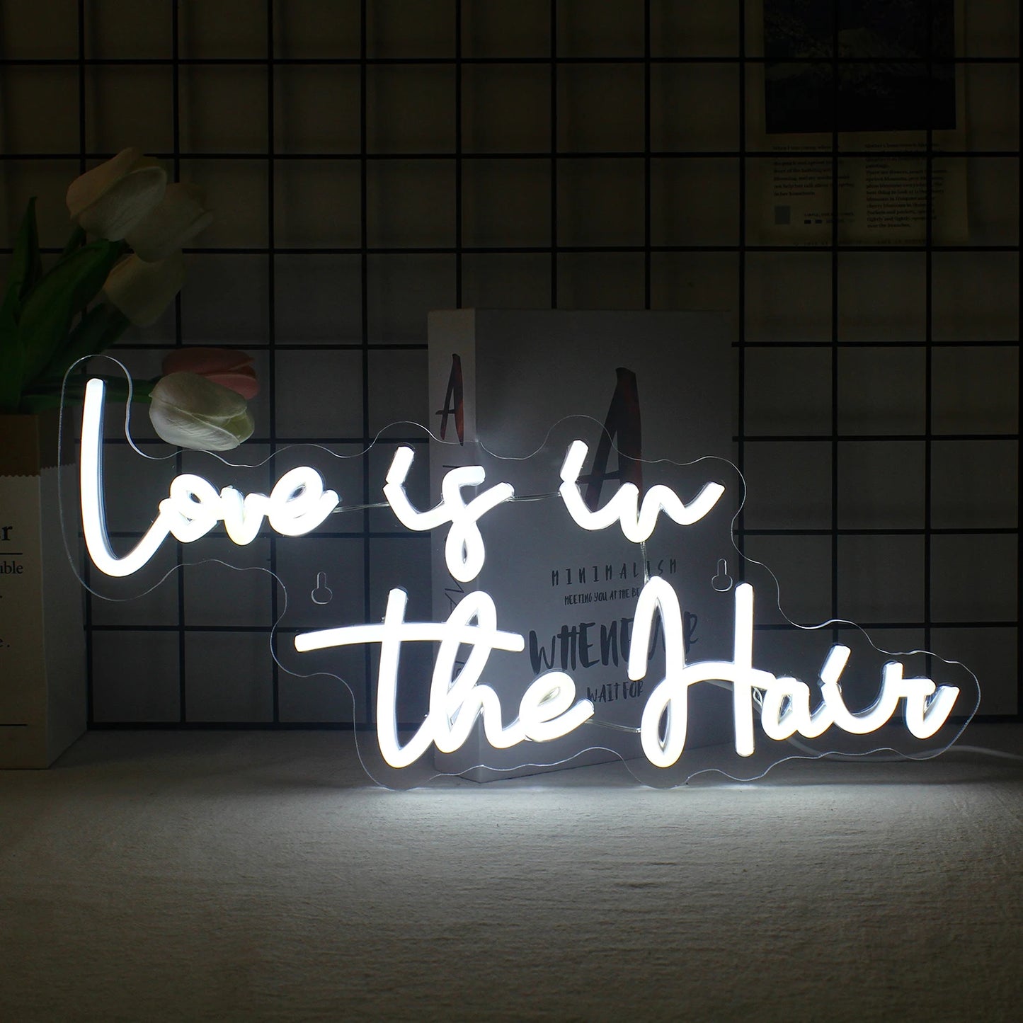 De afbeelding toont een levendig LED-neonbord met de tekst "Love is in the Hair" in een stijlvol, vloeiend lettertype.