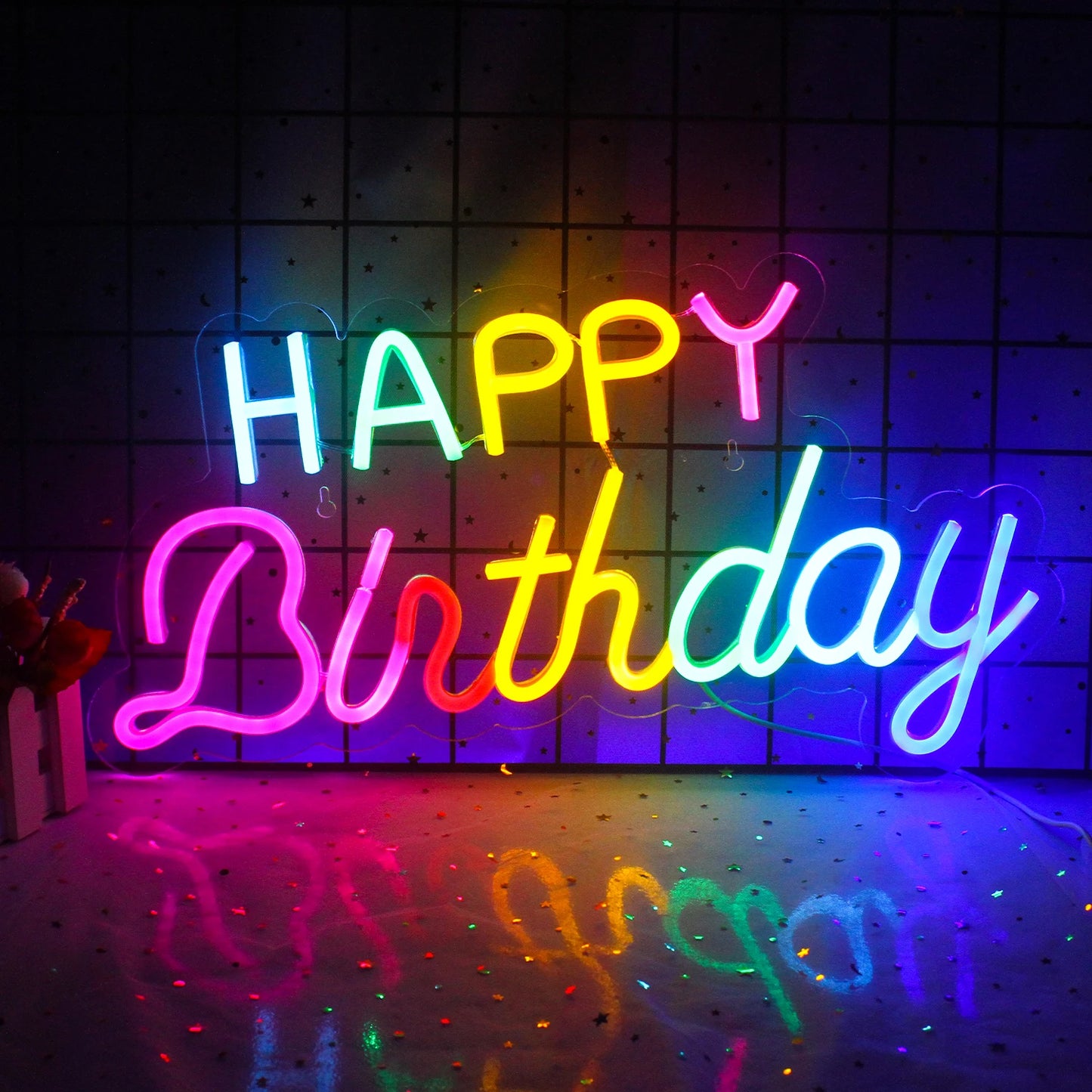 Een levendig "Happy Birthday" LED-neonbord in feestelijke kleuren, gemonteerd op een muur.