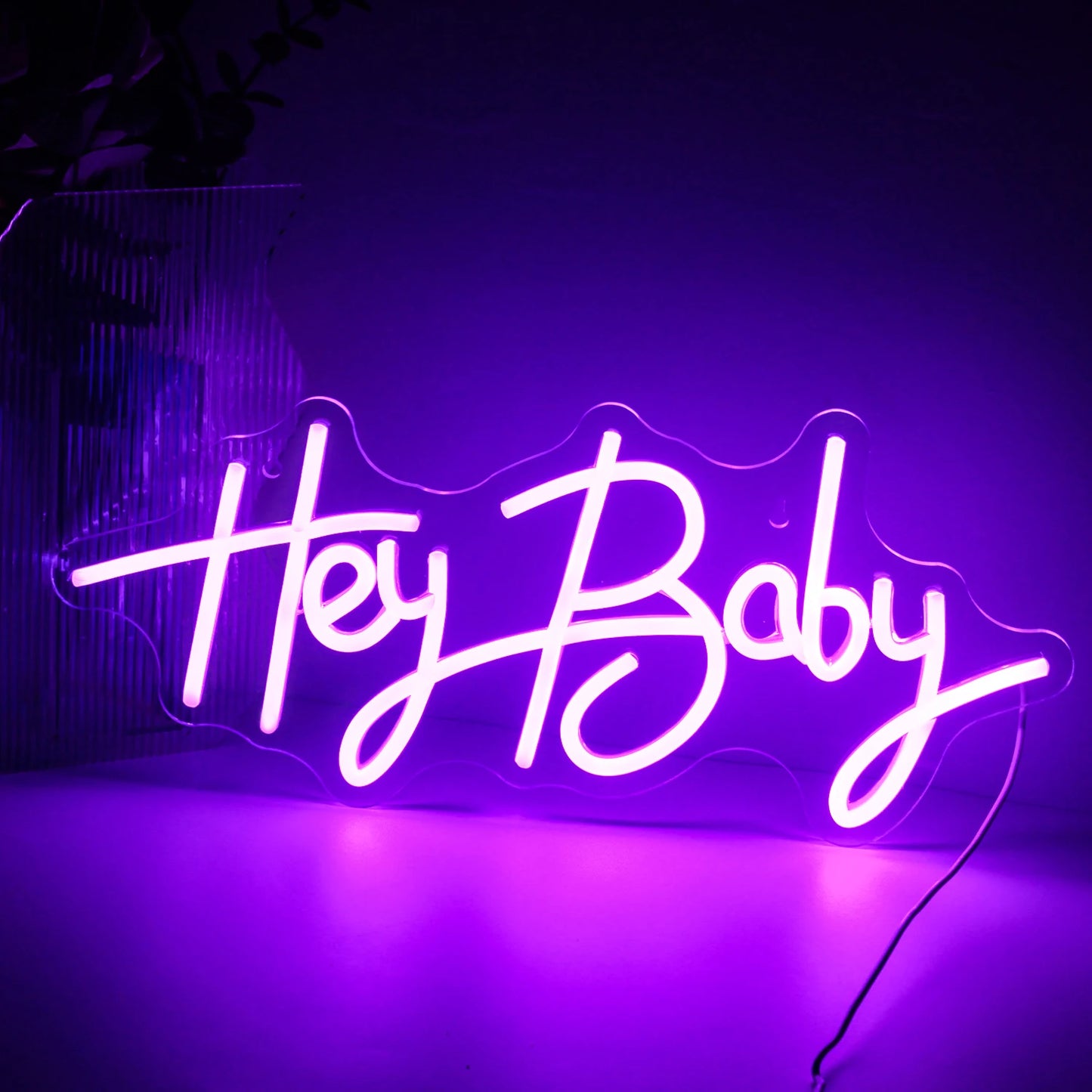Op de afbeelding is een levendig, handgemaakt LED-neonbord te zien met de tekst "Hey Baby" in een speels, cursief lettertype.