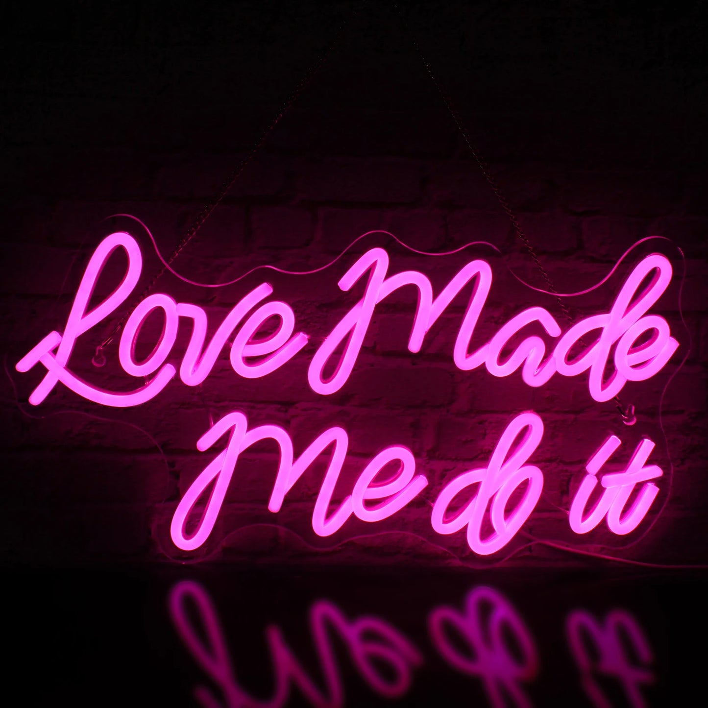De afbeelding toont een levendig LED-neonbord met de tekst "Love Made Me Do It" in een stijlvol, cursief lettertype.