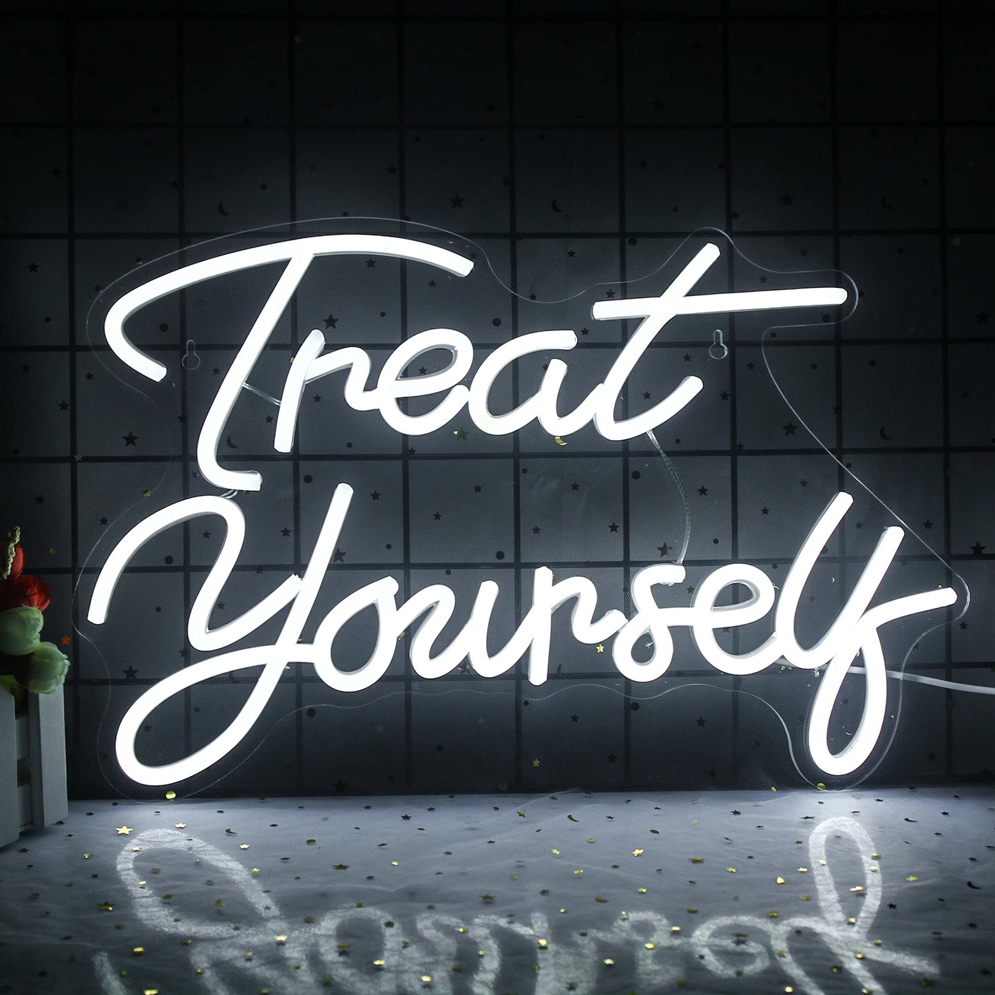 De afbeelding toont een levendig LED-neonbord met de tekst "Treat Yourself" in een speels, cursief lettertype.