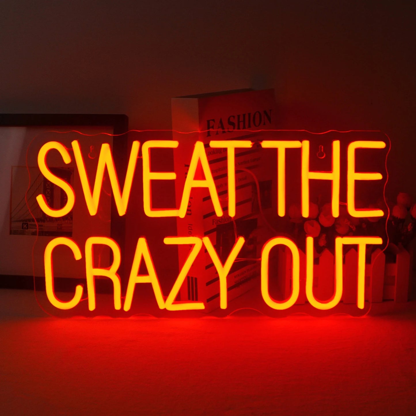 Een levendig LED-neonbord met de tekst "Sweat The Crazy Out" in een speels, cursief lettertype.