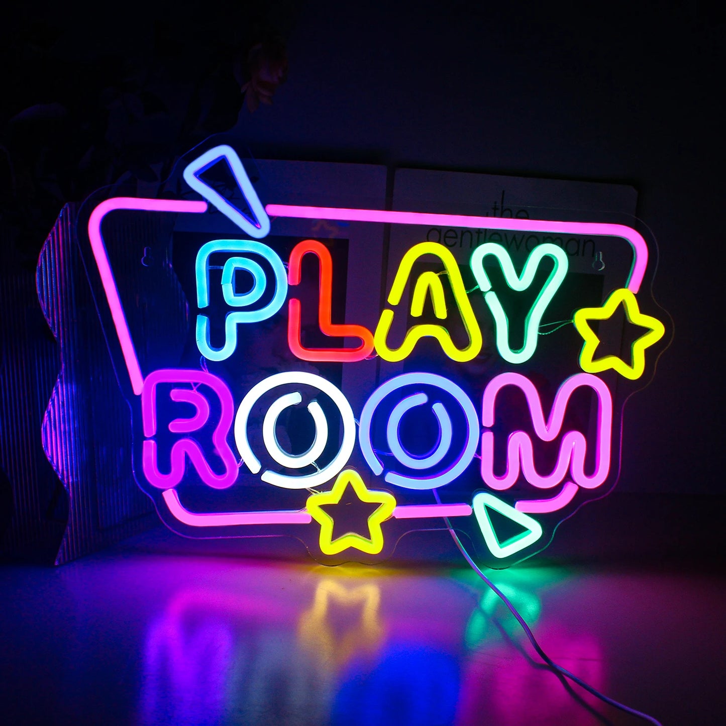 Op de afbeelding is een opvallend led-neonbord te zien met de tekst 'Play Room' in vrolijke, speelse kleuren.