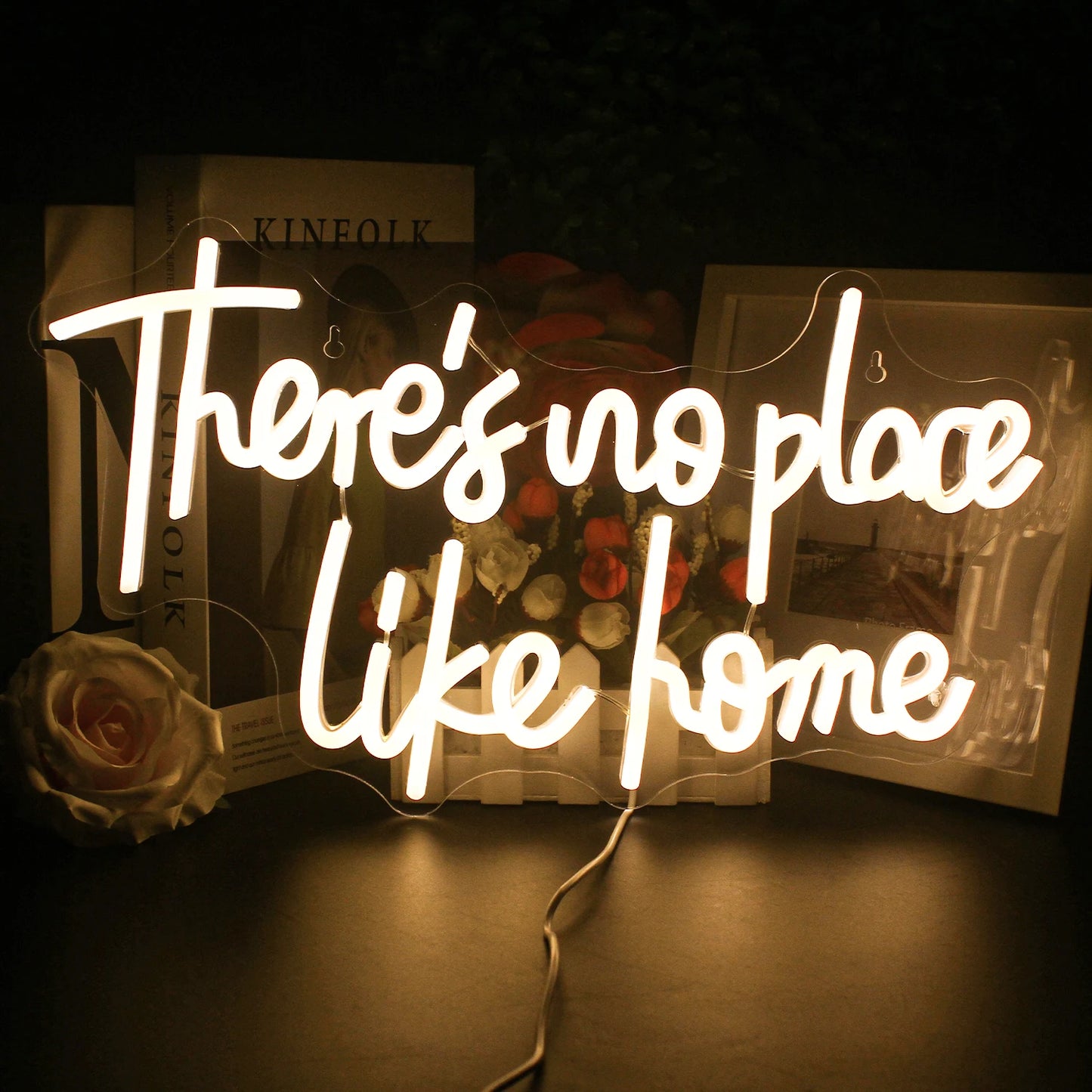 Op de afbeelding staat een stijlvol en levendig LED-neonbord met de tekst: "There's No Place Like Home.