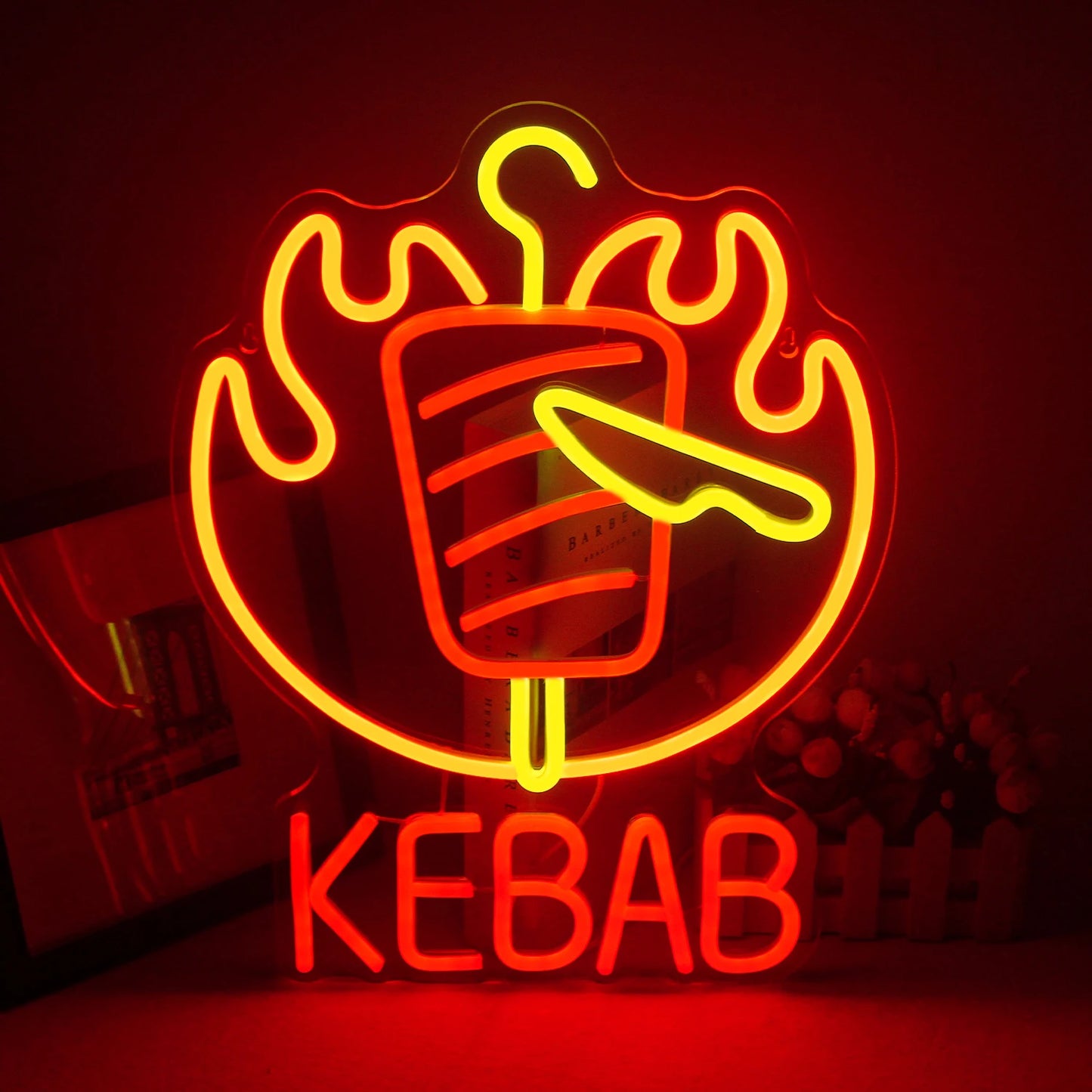 Op de afbeelding is een opvallend LED-neonreclamebord te zien in de vorm van een kebabspies.