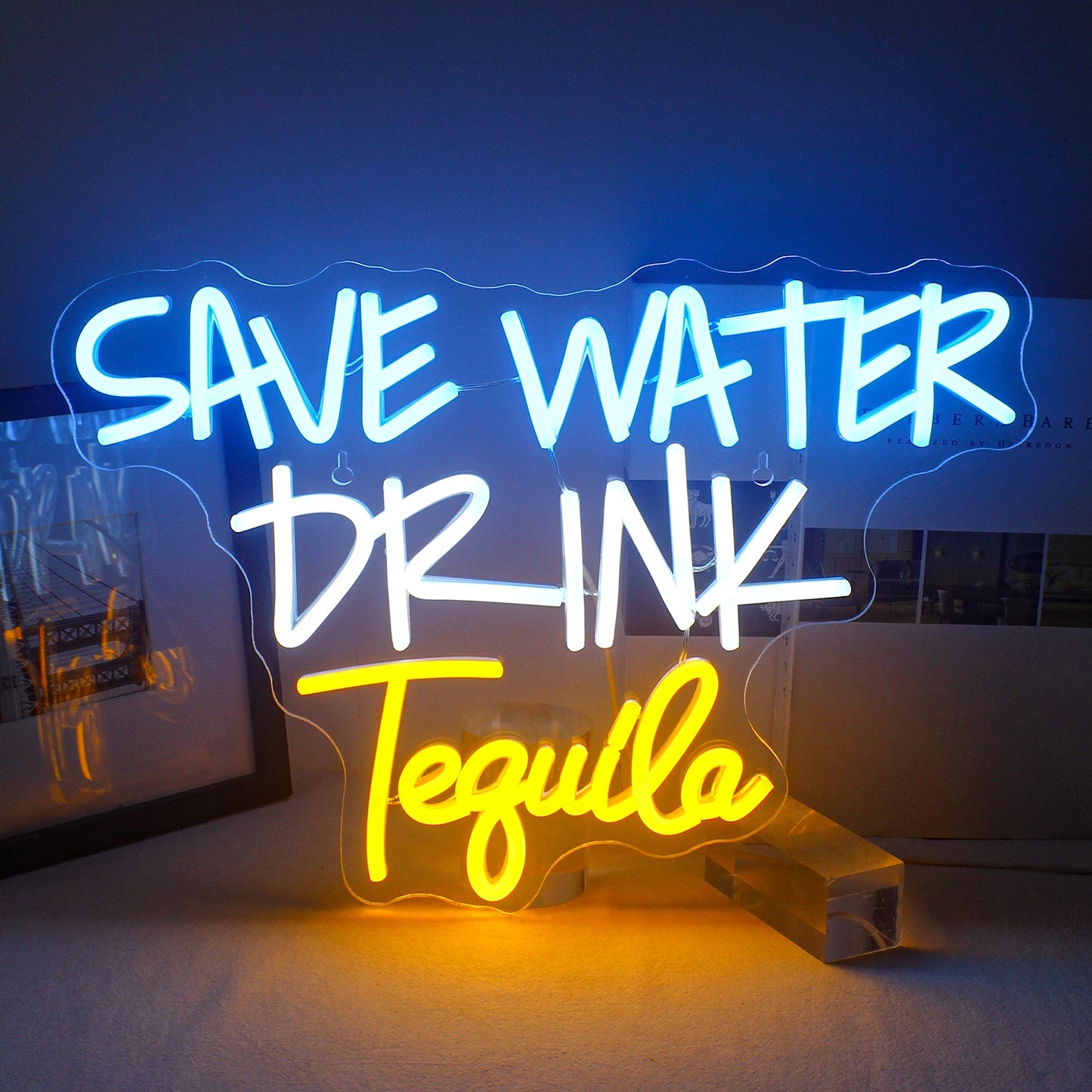 De afbeelding toont een levendig LED-neonbord met de tekst "Save Water Drink Tequila" in opvallende, speelse letters.