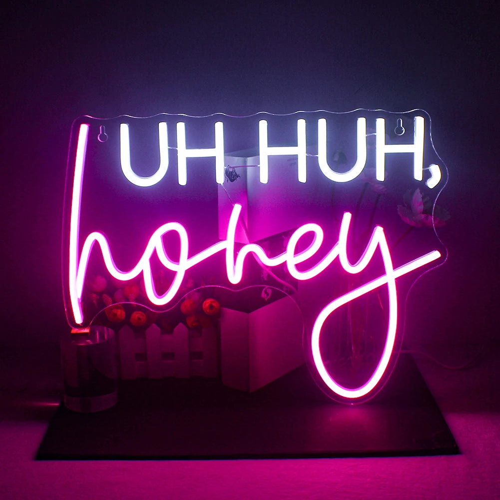 Op de afbeelding staat een levendig, handgemaakt LED-neonbord met de tekst "Uh Huh" in levendig, cursief schrift.