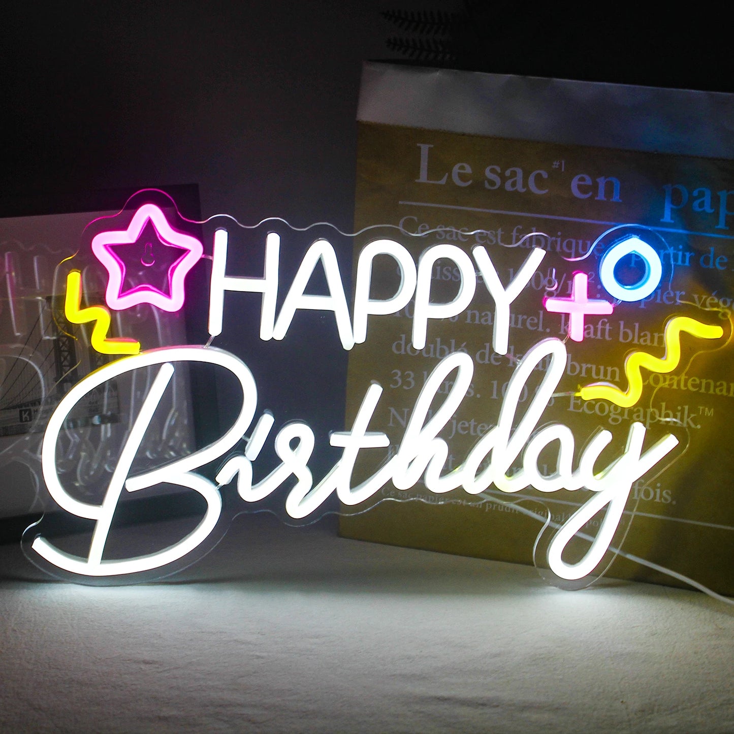 Een levendig "Happy Birthday" LED-neonbord tegen een donkere achtergrond.