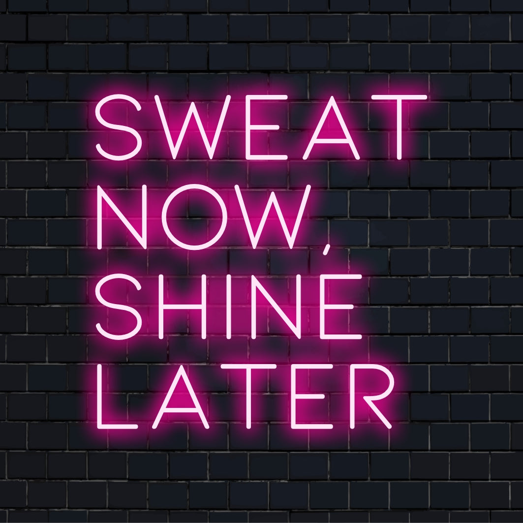 Een op maat gemaakt LED-neonbord met de motiverende quote Sweat Now, Shine Later, perfect als inspirerende wanddecoratie.
