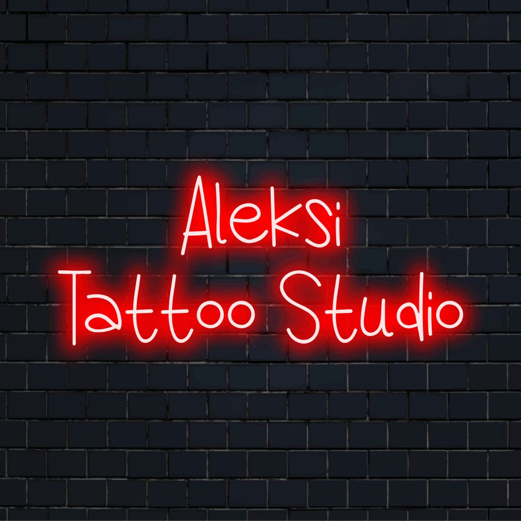 Aleksi Tattoo Studio Custom Name Neon Sign, bright neon glow against black brick wall