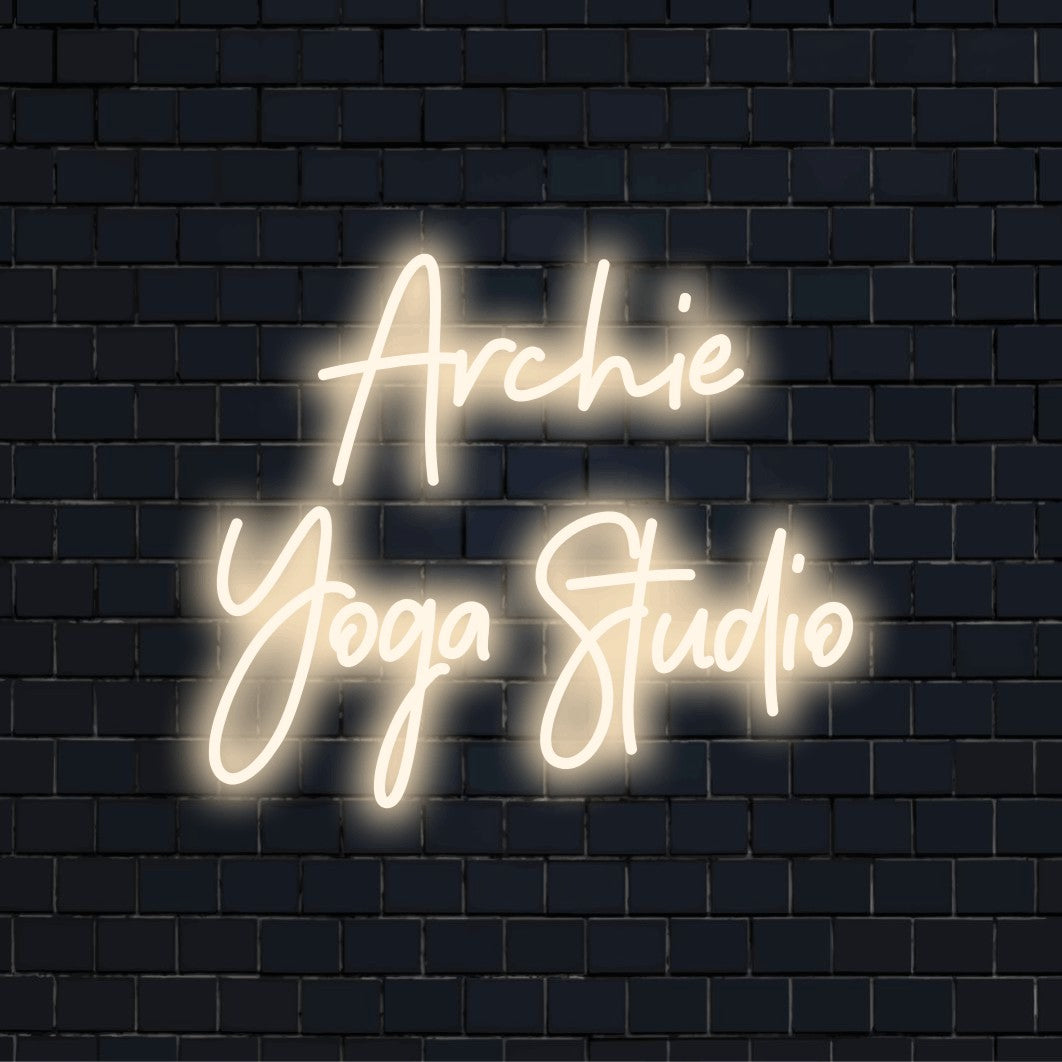 Archie Yoga Studio Personalized Neon Light with glowing neon text on black brick background