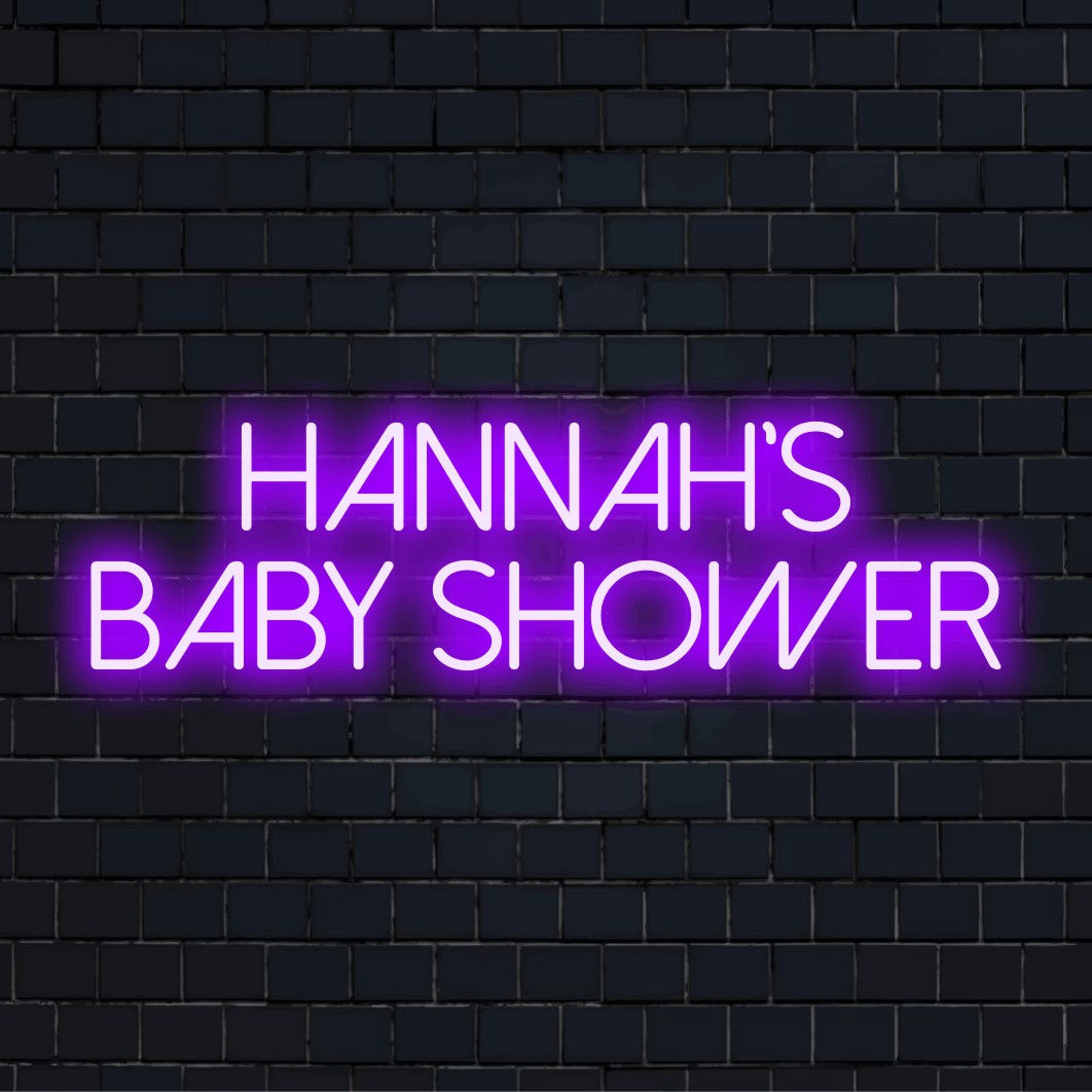 Hannah_s Baby Shower Custom Name Neon Sign, glowing lettering against black brick wall