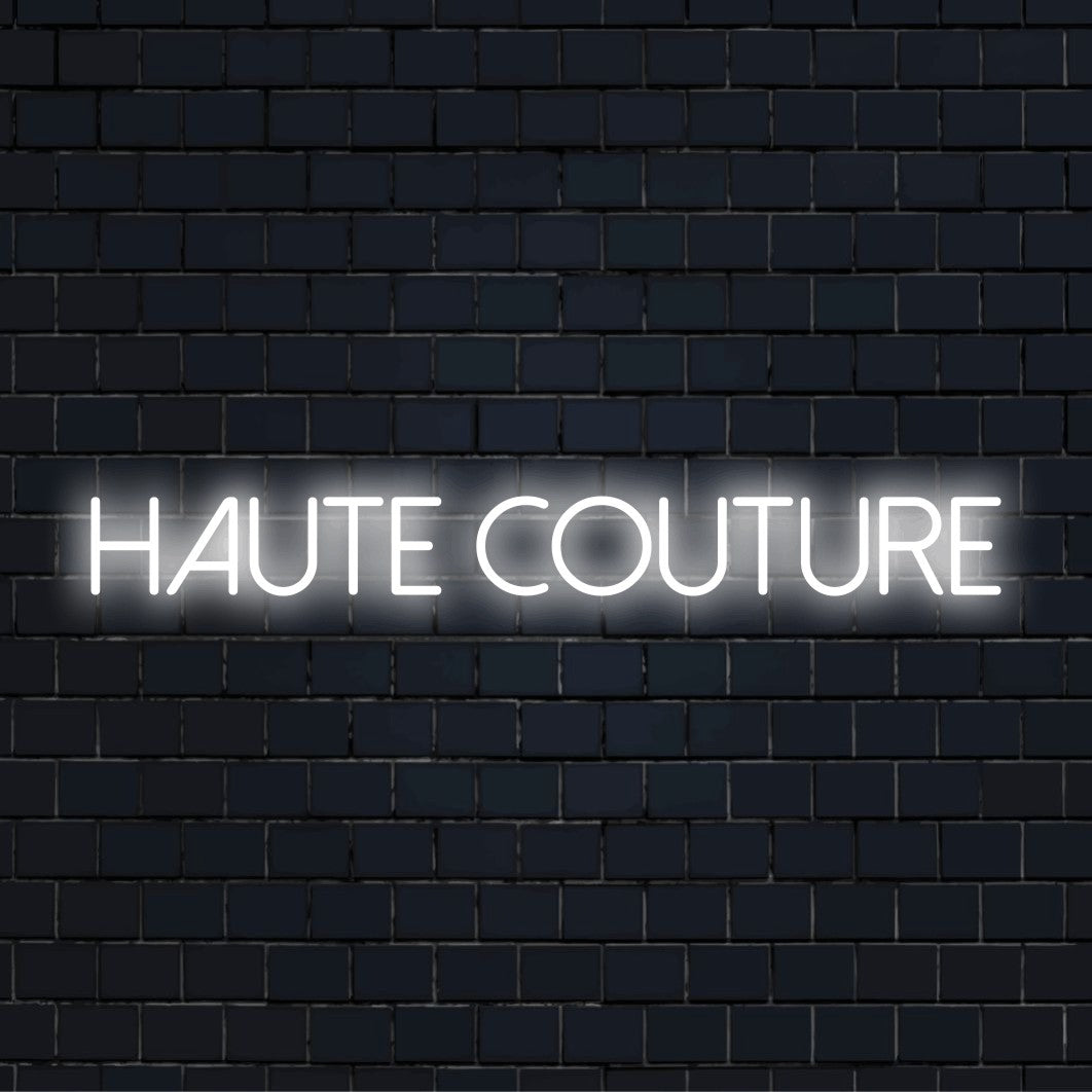 Haute Couture Neon Sign, glowing neon text on dark brick background