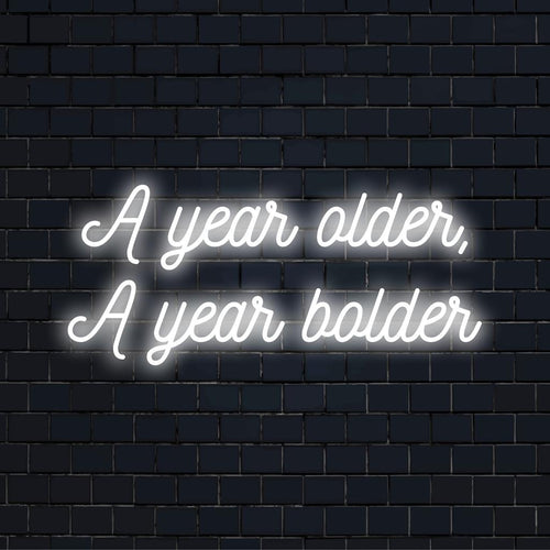 Levendig LED-neonbord met de tekst A Year Older, A Year Bolder als opvallende neonmuurkunst en op maat gemaakte lichtdecoratie.