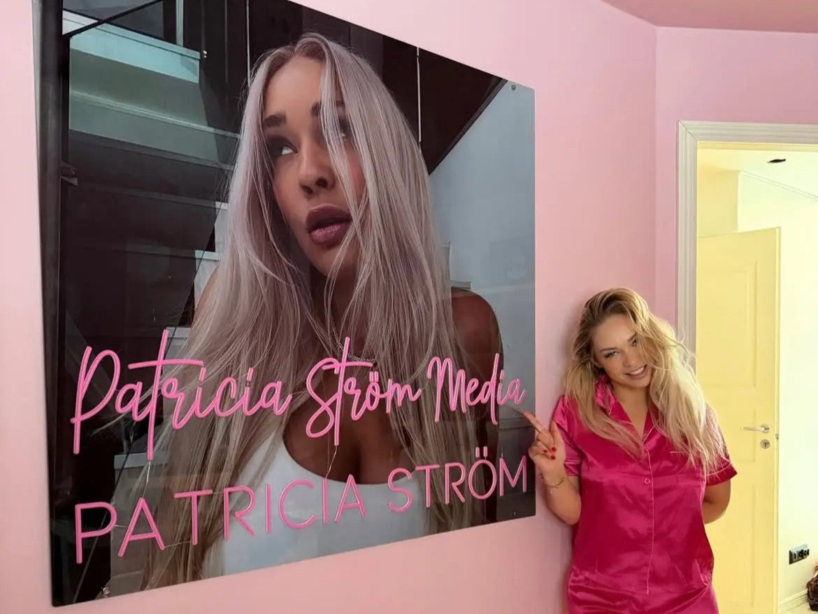 Pink Patricia Ström Media neon logo displayed beside Patricia Ström in her branded workspace