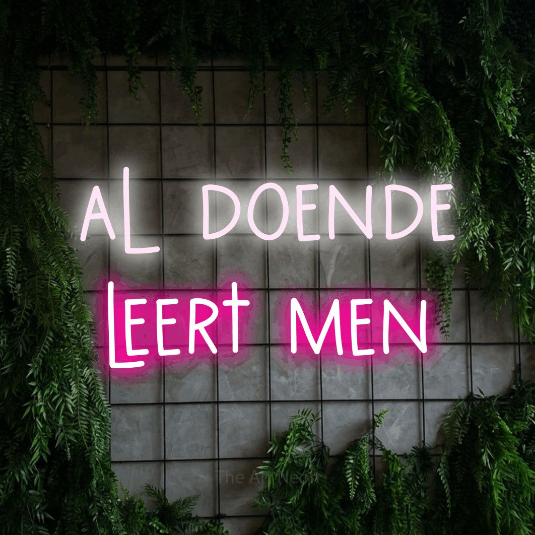 LED neon sign reading “al doende leert men”, arranged in 2 lines.