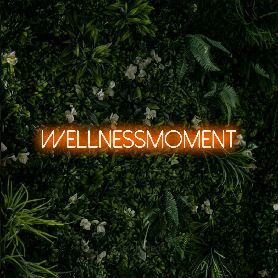 LED neon sign reading “WELLNESSMOMENT”, arranged in a single line.