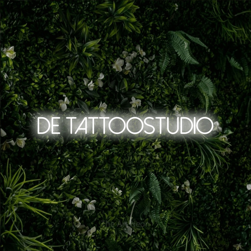 LED neon sign reading “DE tattoostudio”, arranged in a single line.