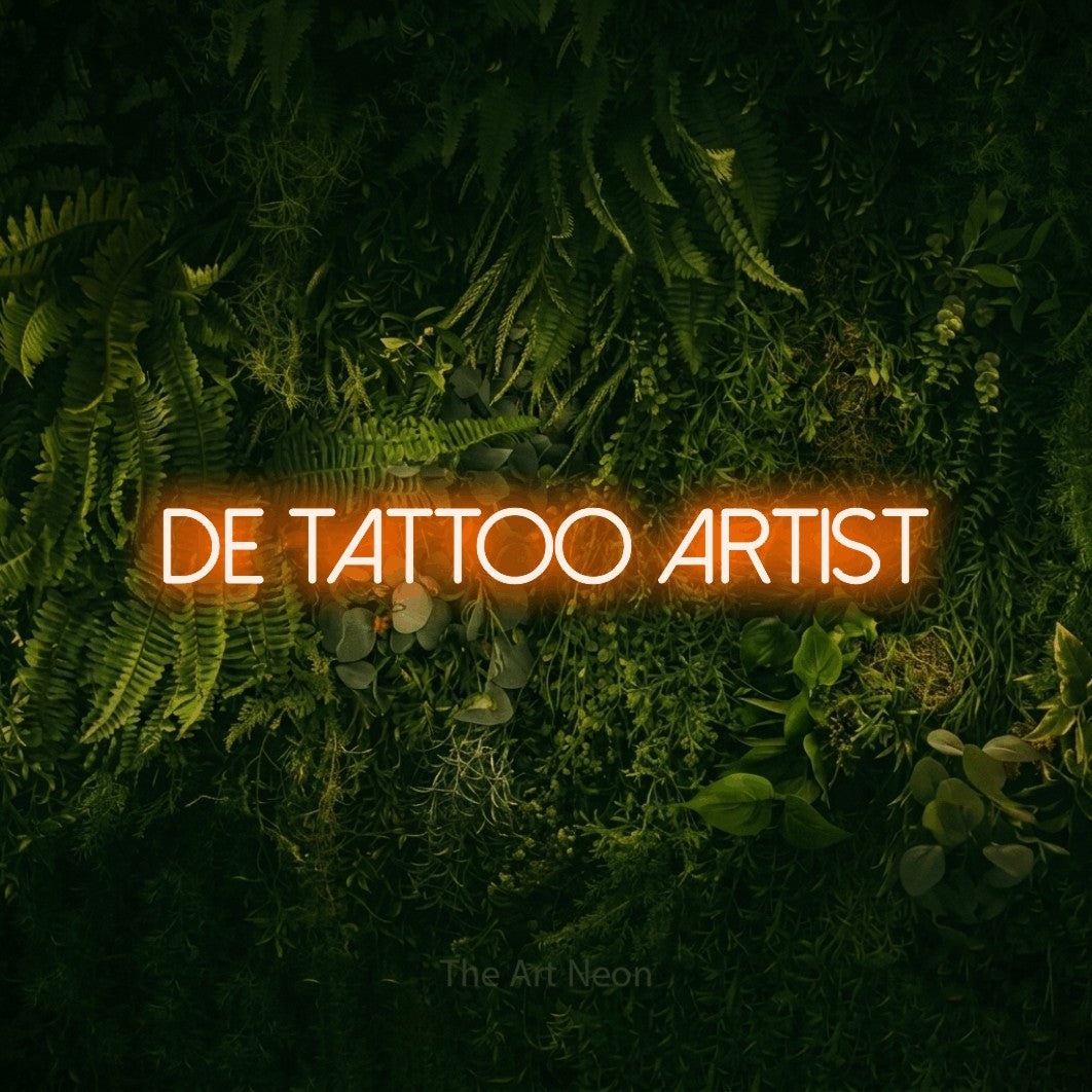 LED neon sign reading “de tattoo artist”, arranged in a single line.
