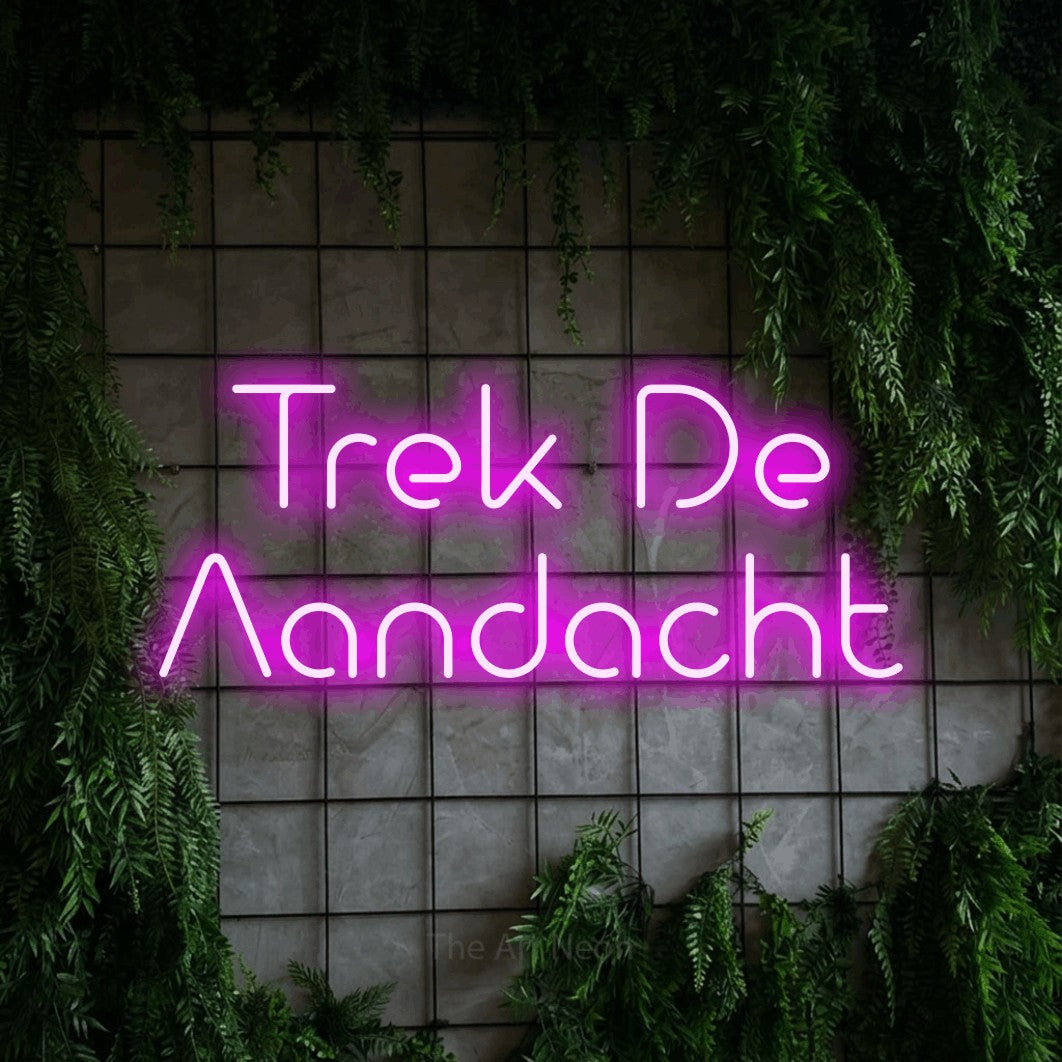 LED neon sign reading “Trek De Aandacht”, arranged in 2 lines.