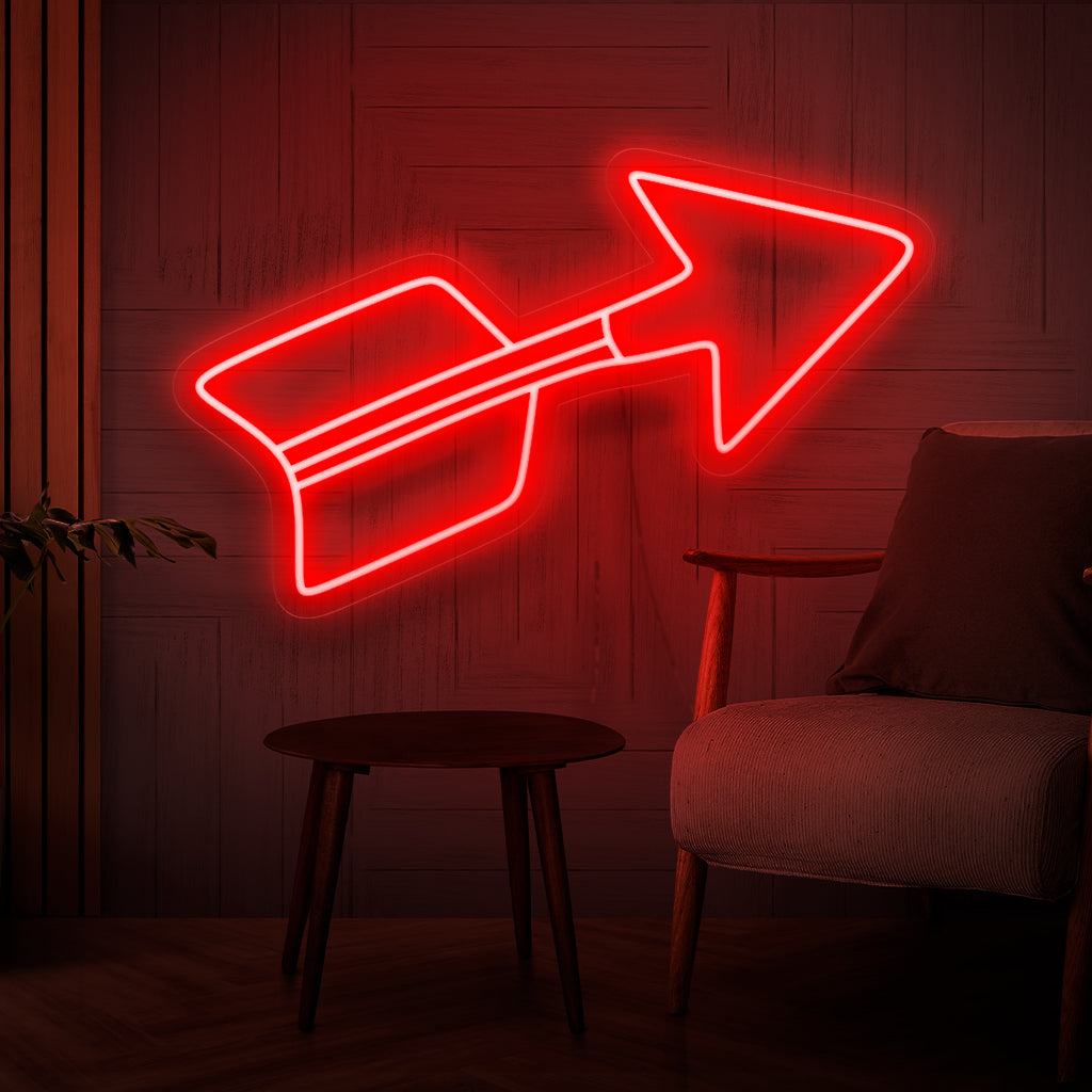 Een verlicht neonbord met een opvallende rode pijl, die de richting symboliseert en naar een stijlvol en decoratief element wijst, dat een boeiend middelpunt vormt in elke ruimte.