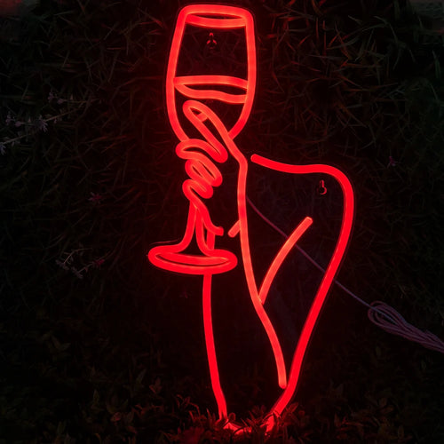 De afbeelding toont een levendig led-neonbord met de omtrek van een vrouw die een wijnglas vasthoudt.