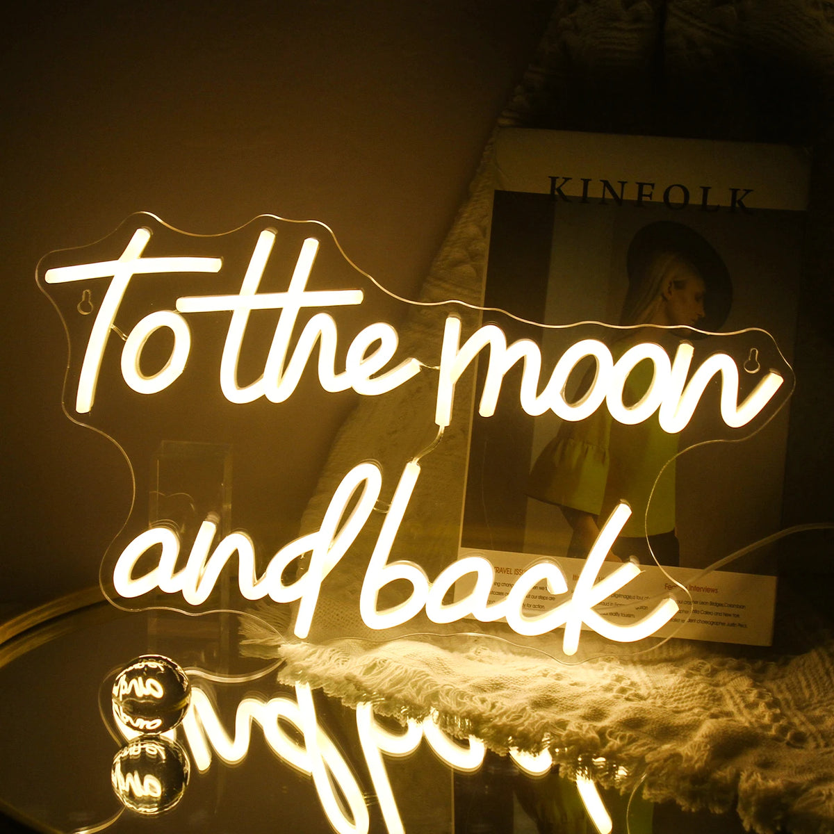 Op de afbeelding staat een handgemaakt LED-neonbord met de tekst "To The Moon And Back" in elegante, cursieve letters.