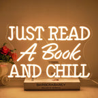 The image features a vibrant LED neon sign that spells out the phrase "Just Read A Book And Chill.
