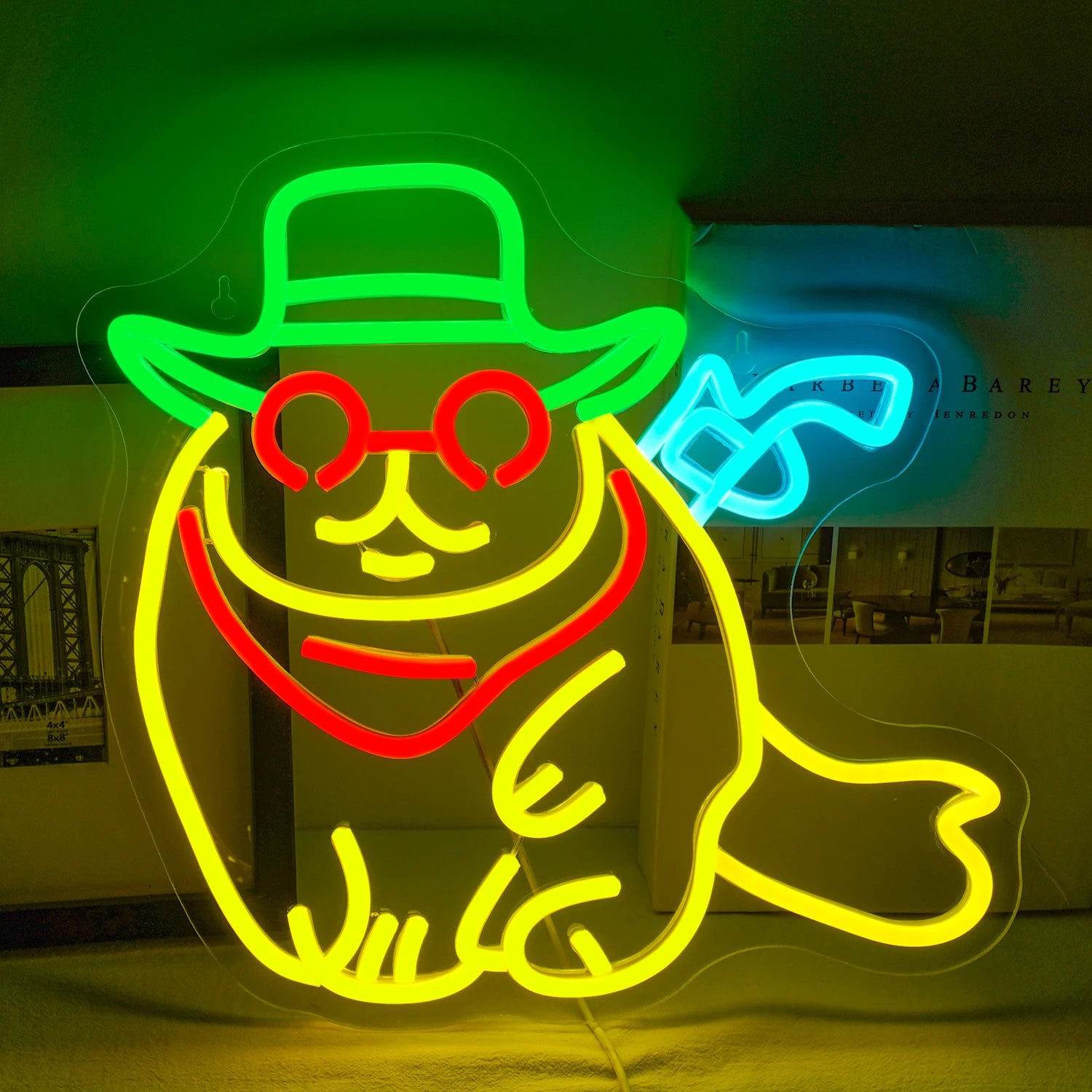 The image features a LED neon sign shaped like a cartoon cat dressed as a cowboy.